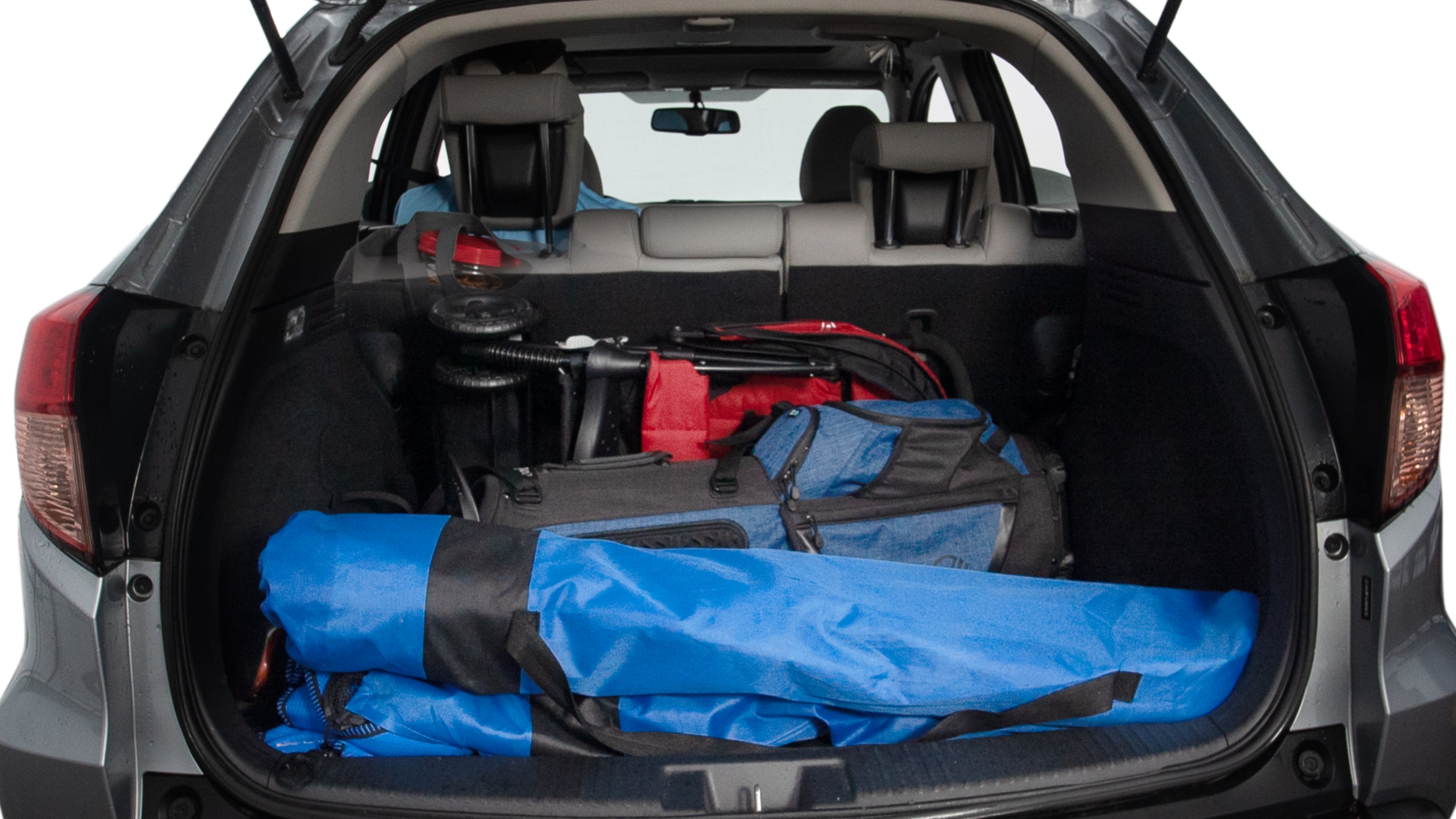The trunk lid is open showing full view of the trunk. A baby stroller, three grocery carriers, two camping chairs in the carrying bag, and a set of golf clubs are placed inside.