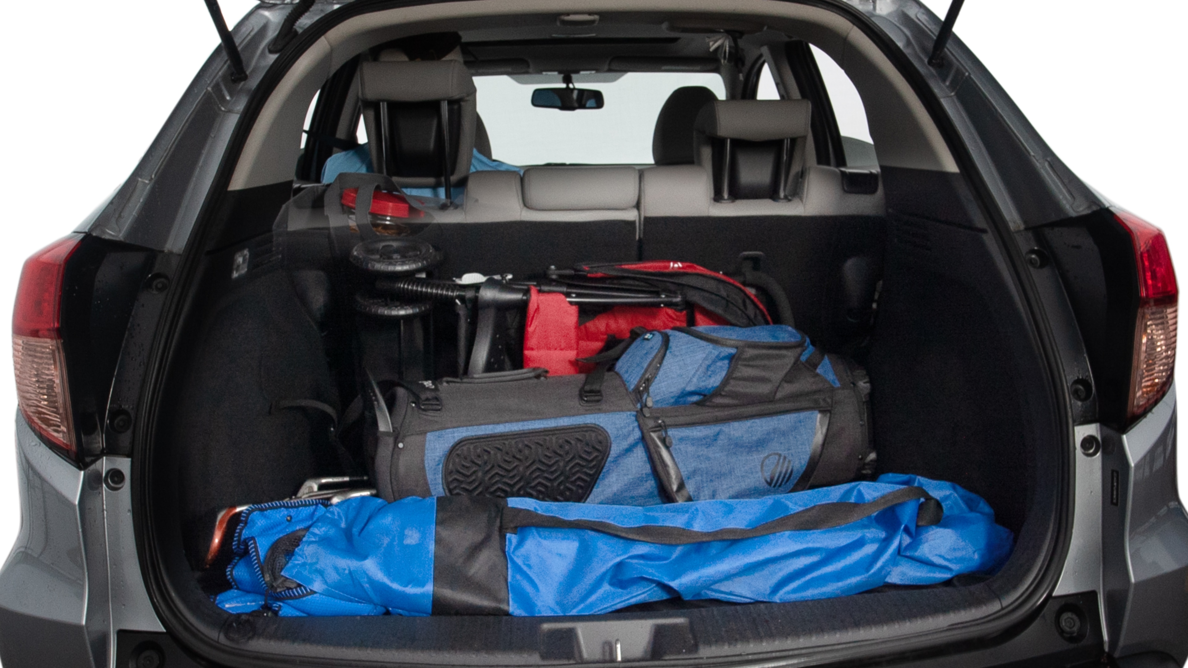 The trunk lid is open showing full view of the trunk. A baby stroller, three grocery carriers, two camping chairs in the carrying bag, and a set of golf clubs are placed inside.