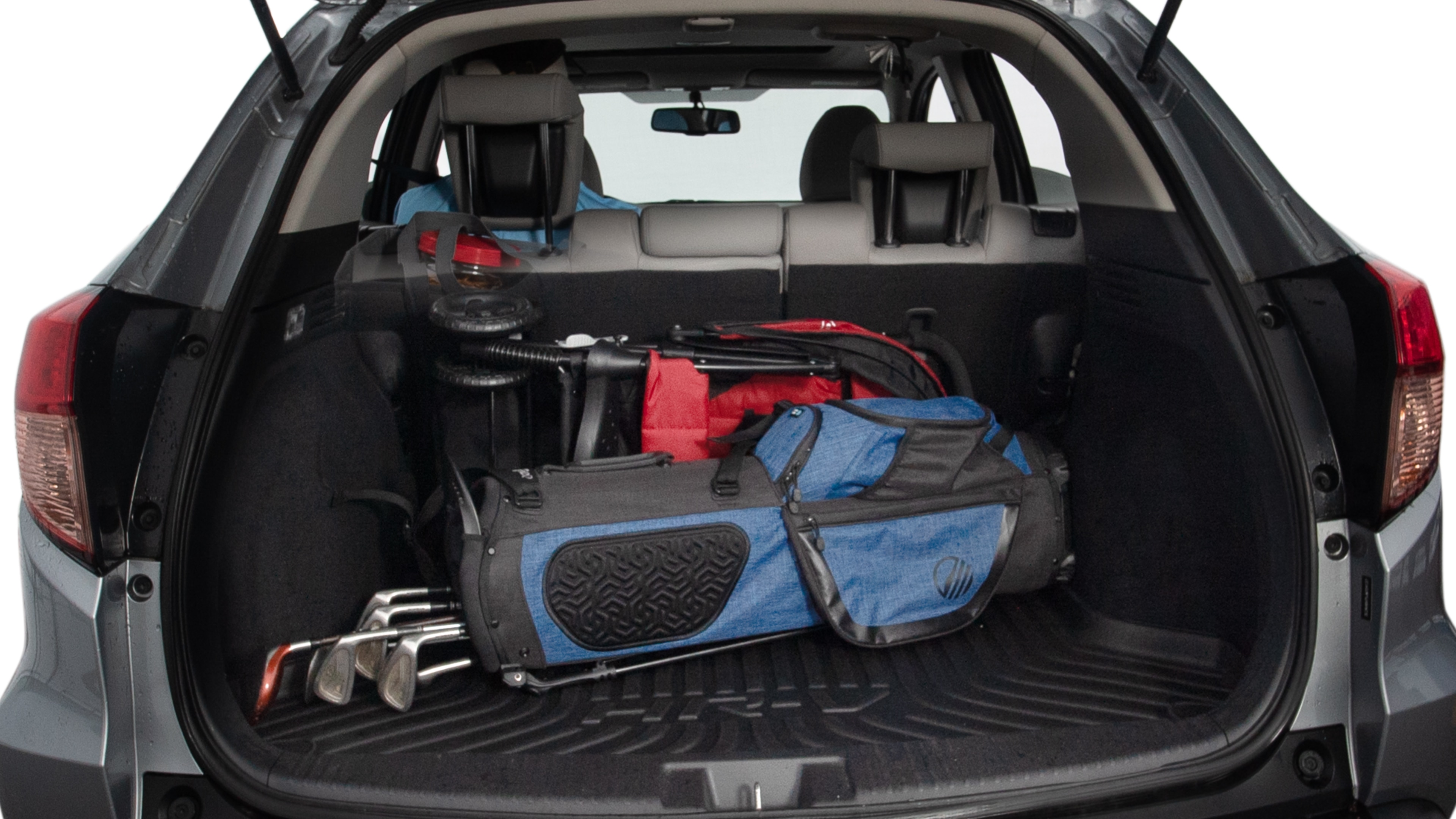 The trunk lid is open showing full view of the trunk. A baby stroller, three grocery carriers, two camping chairs in the carrying bag, and a set of golf clubs are placed inside.