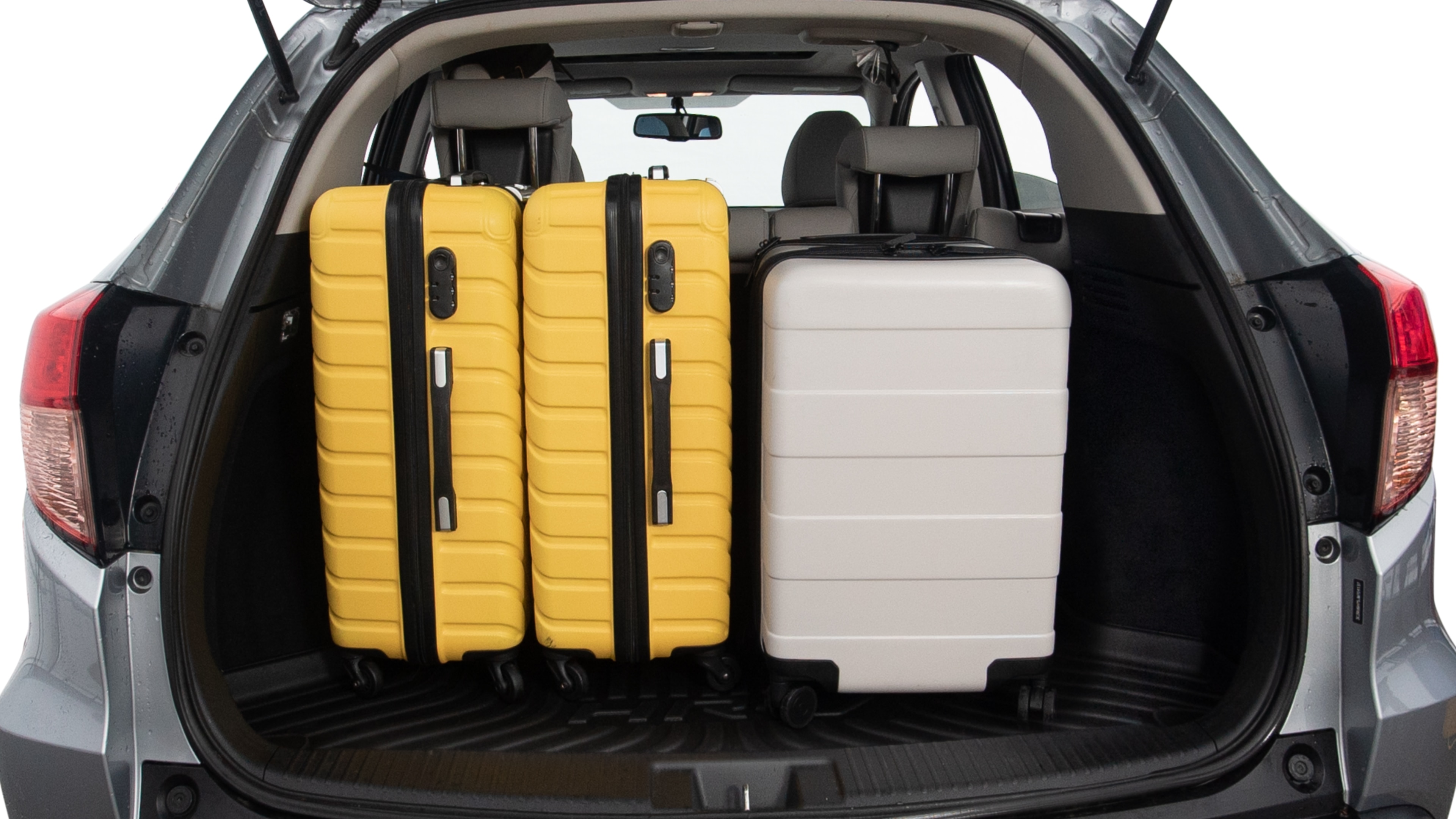The trunk lid is open, showing full view of the trunk space. Two large and two small suitcases are placed inside.