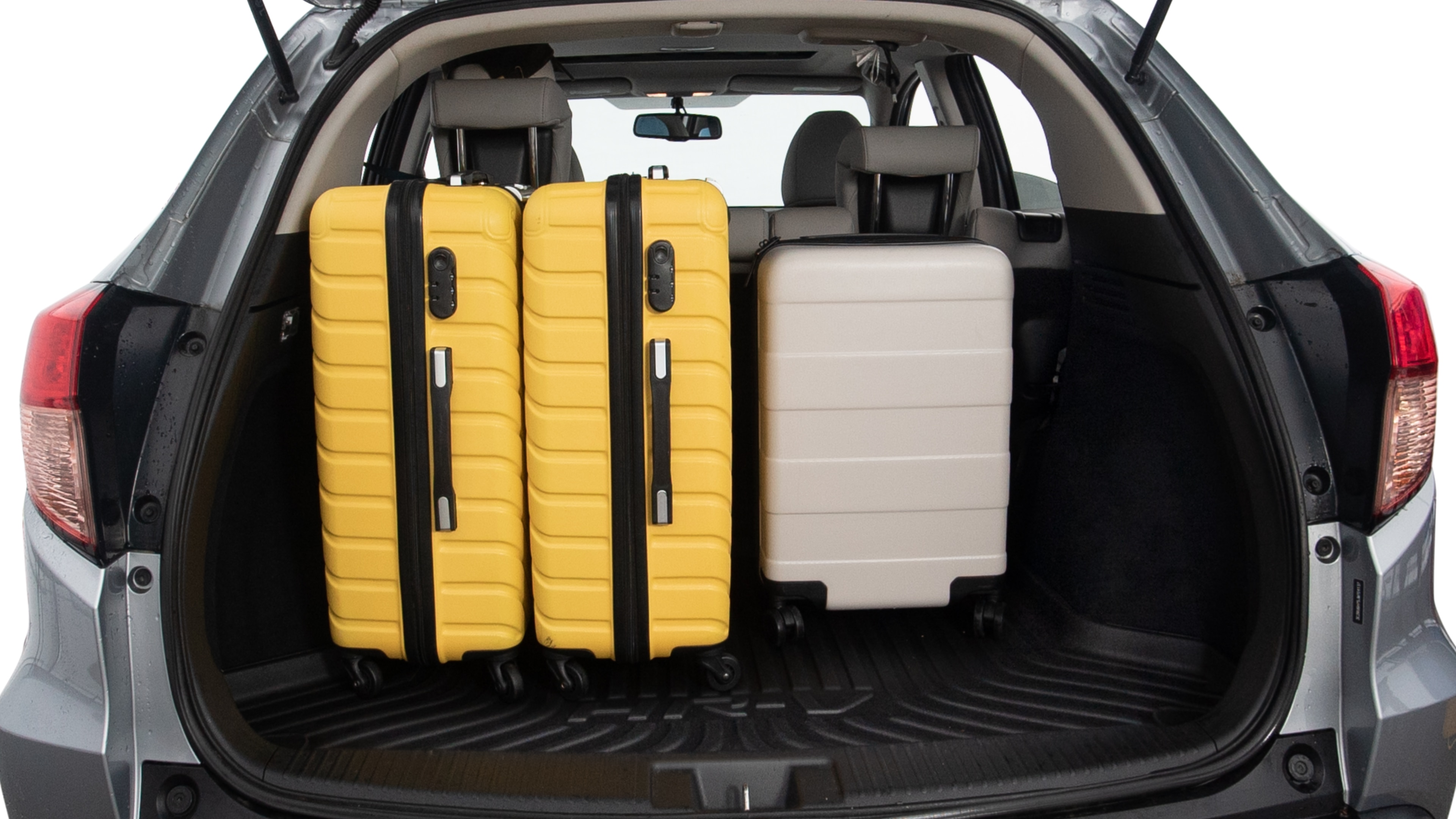 The trunk lid is open, showing full view of the trunk space. Two large and two small suitcases are placed inside.