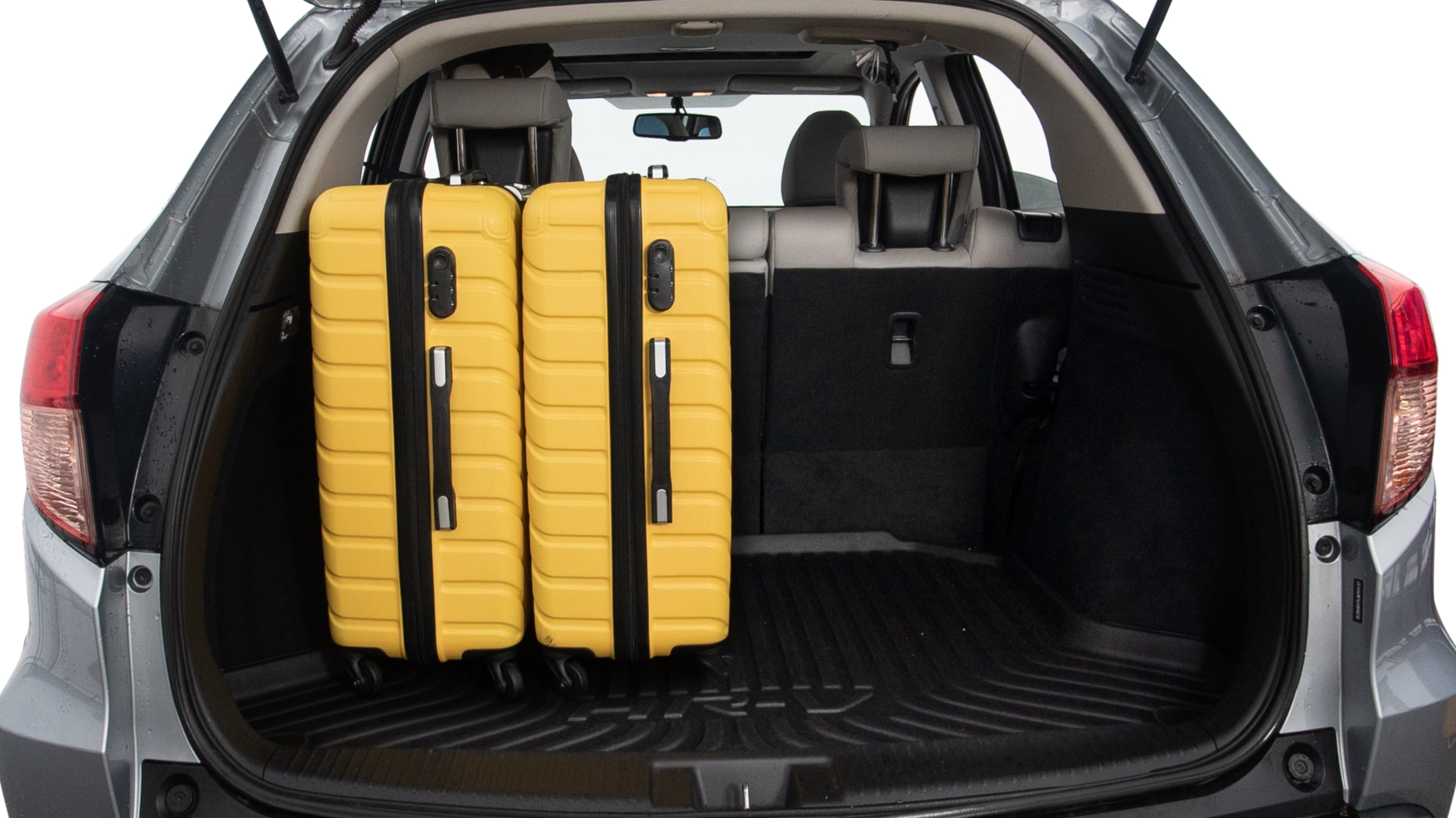 The trunk lid is open, showing full view of the trunk space. Two large and two small suitcases are placed inside.