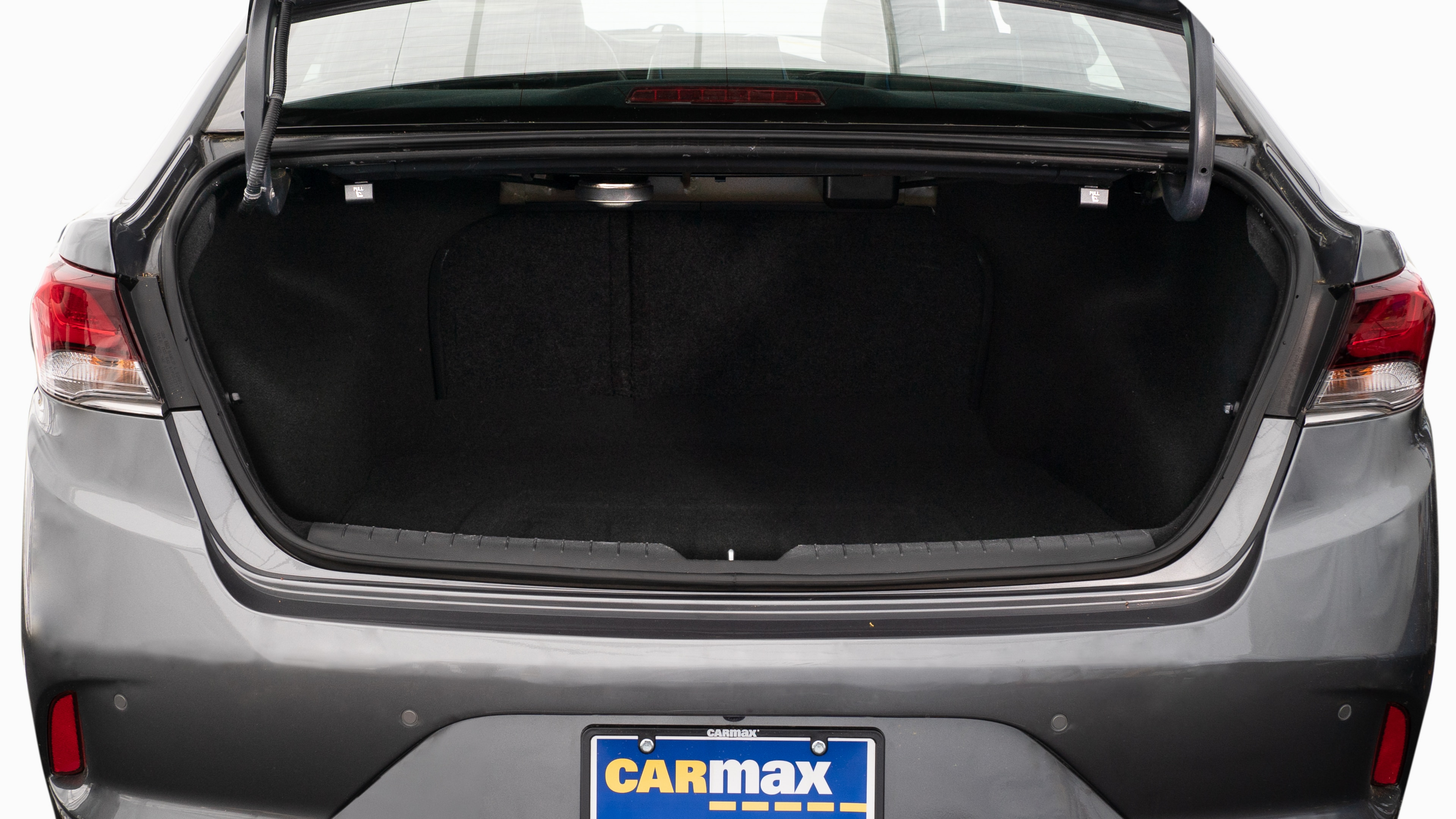 The trunk lid is open showing full view of the trunk. A baby stroller, two grocery carriers, two camping chairs in the carrying bag, and a set of golf clubs are placed inside.