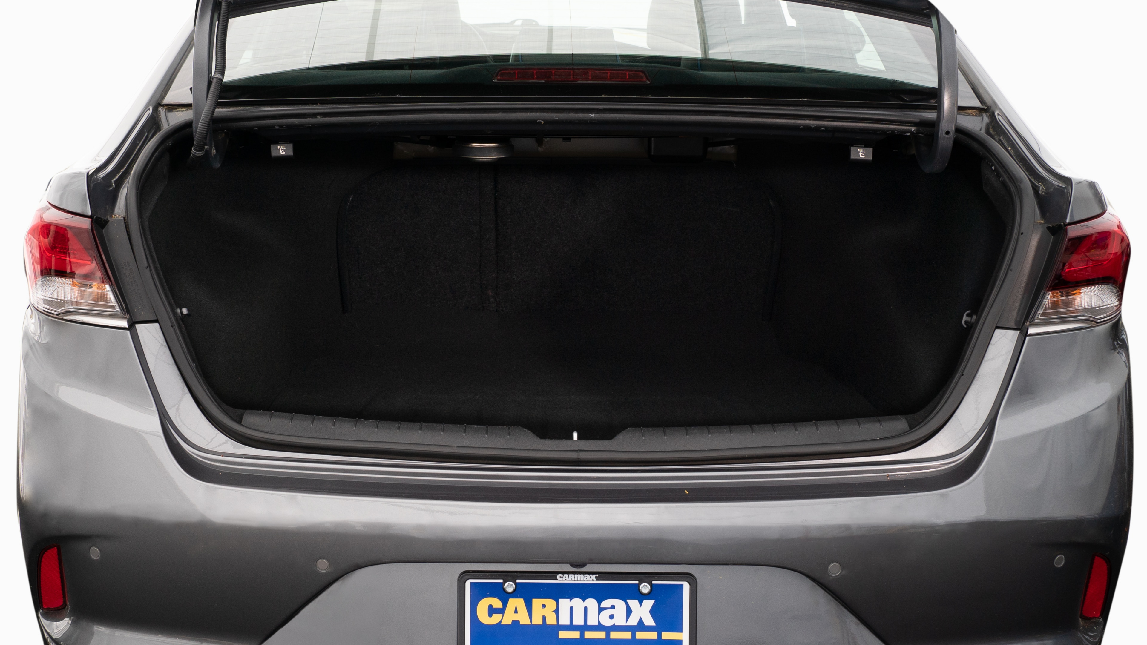 The trunk lid is open, showing a full view of the trunk space. Two large and two small suitcases are placed on their sides.