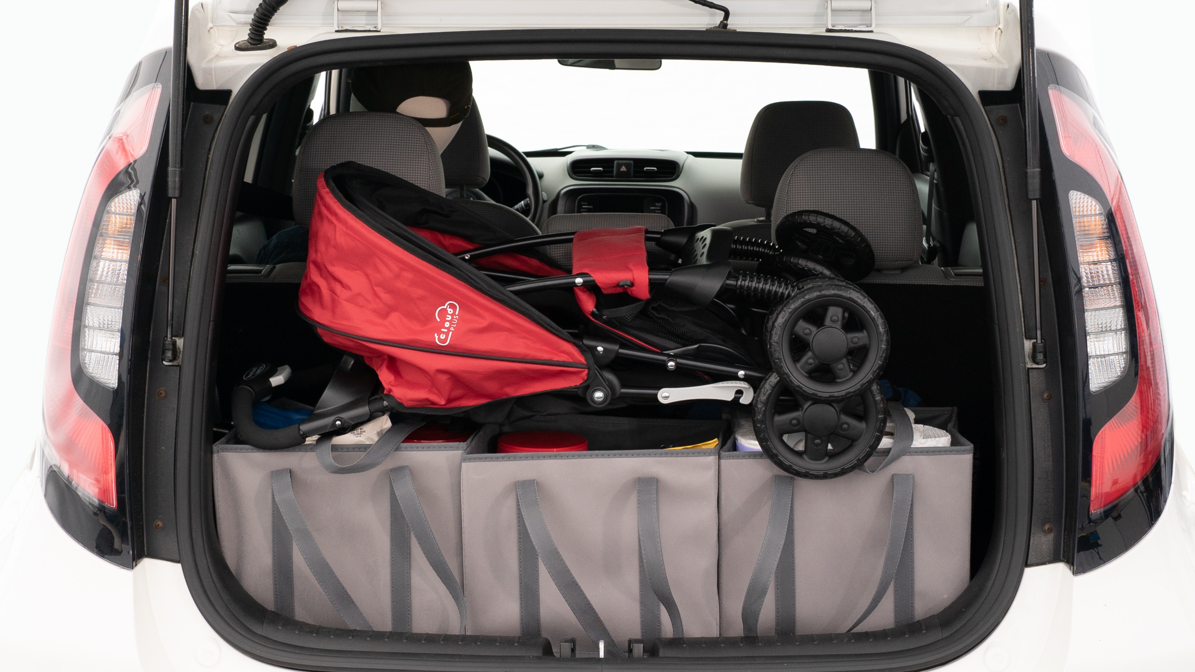 The trunk lid is open showing full view of the trunk. A baby stroller, three grocery carriers, and a set of golf clubs are placed inside.