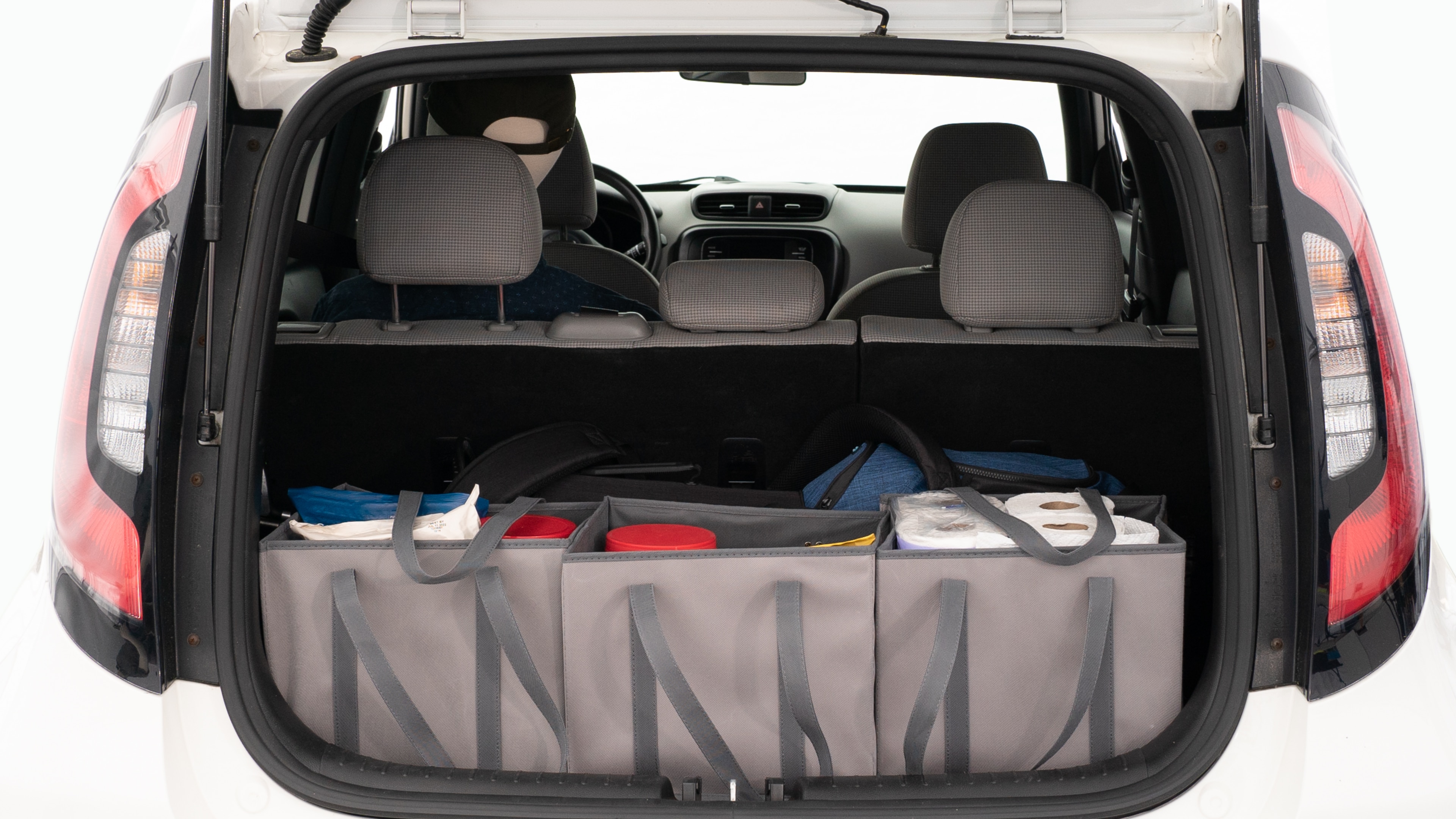 The trunk lid is open showing full view of the trunk. A baby stroller, three grocery carriers, and a set of golf clubs are placed inside.