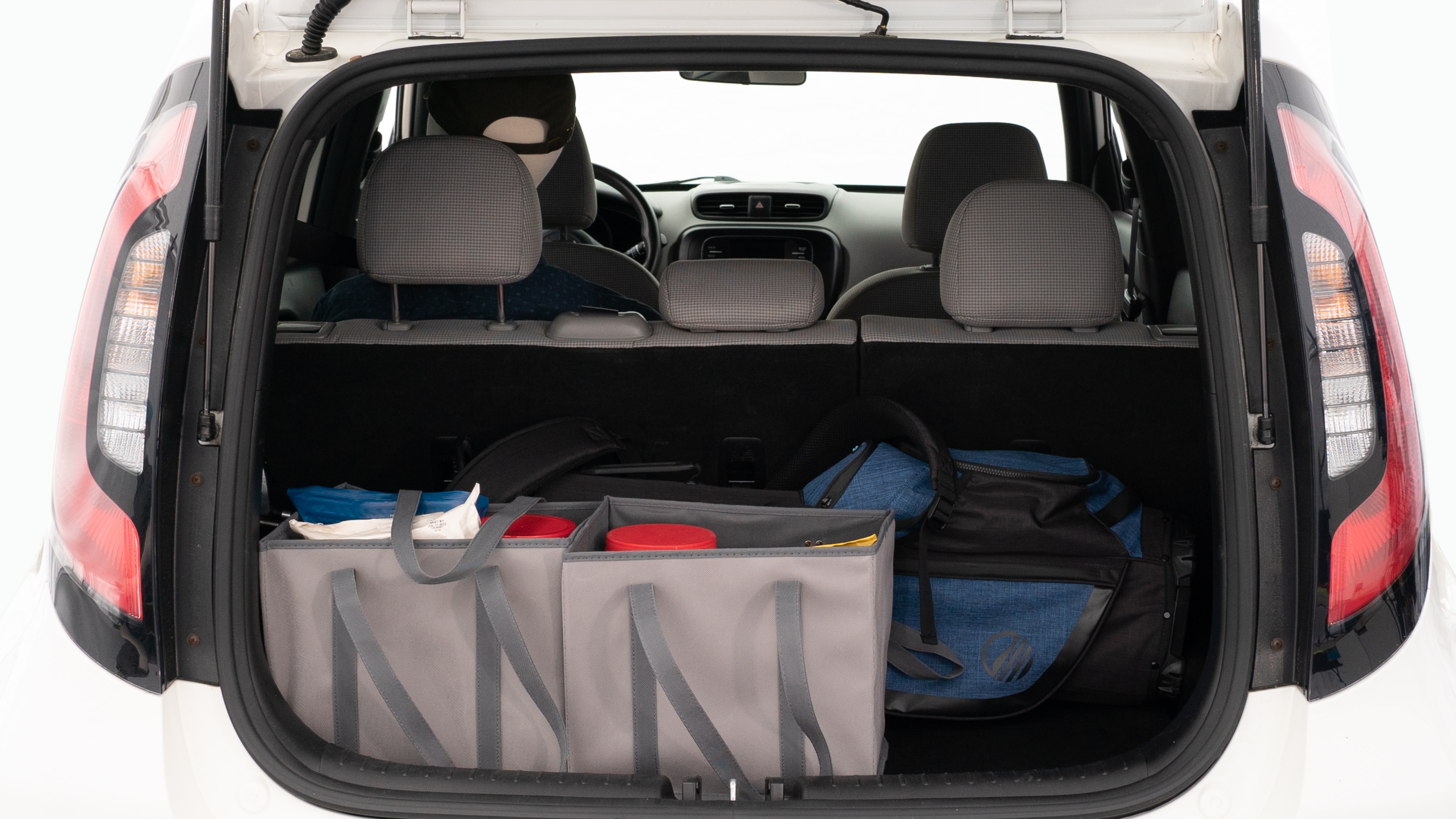 The trunk lid is open showing full view of the trunk. A baby stroller, three grocery carriers, and a set of golf clubs are placed inside.