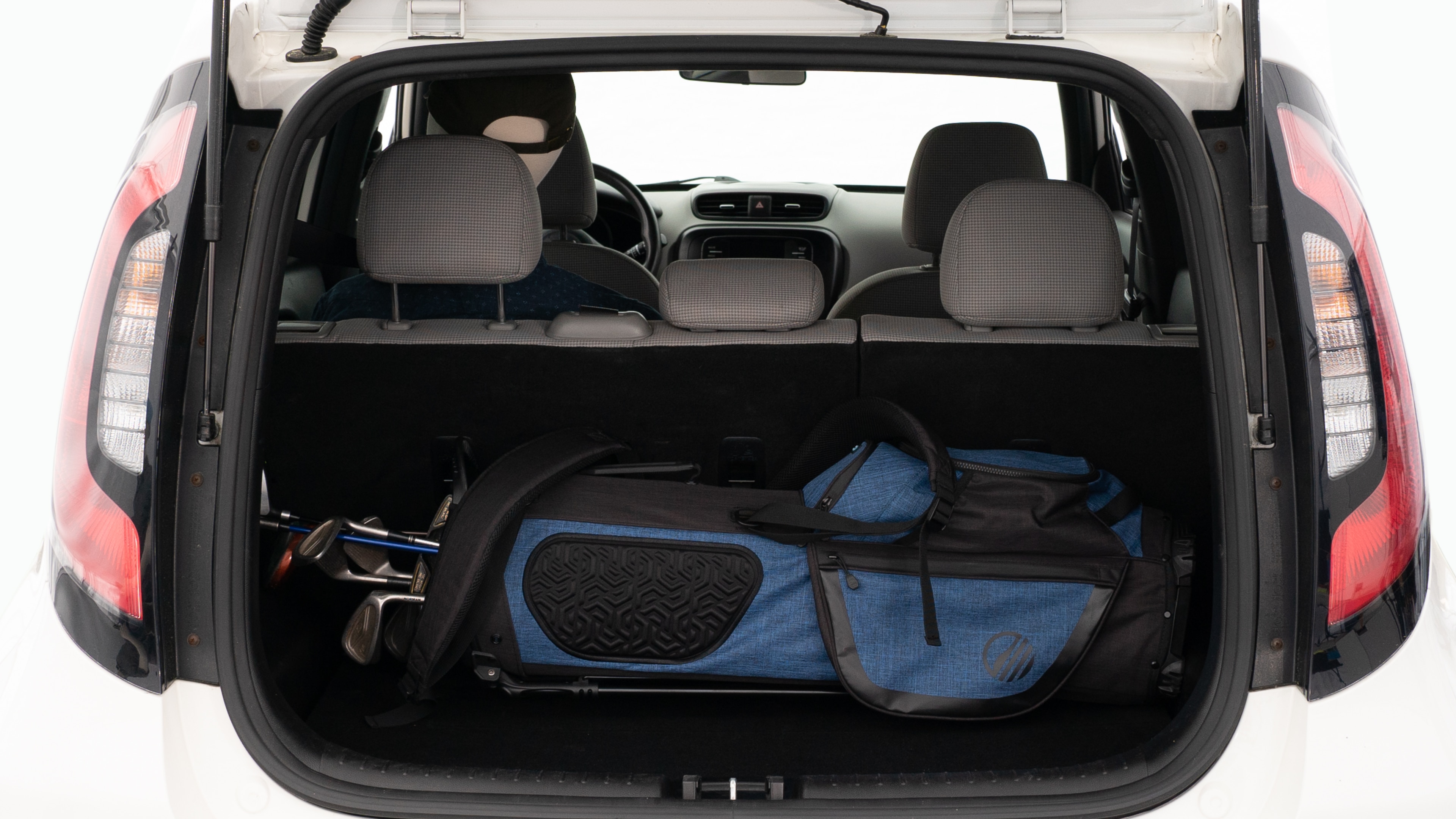 The trunk lid is open showing full view of the trunk. A baby stroller, three grocery carriers, and a set of golf clubs are placed inside.