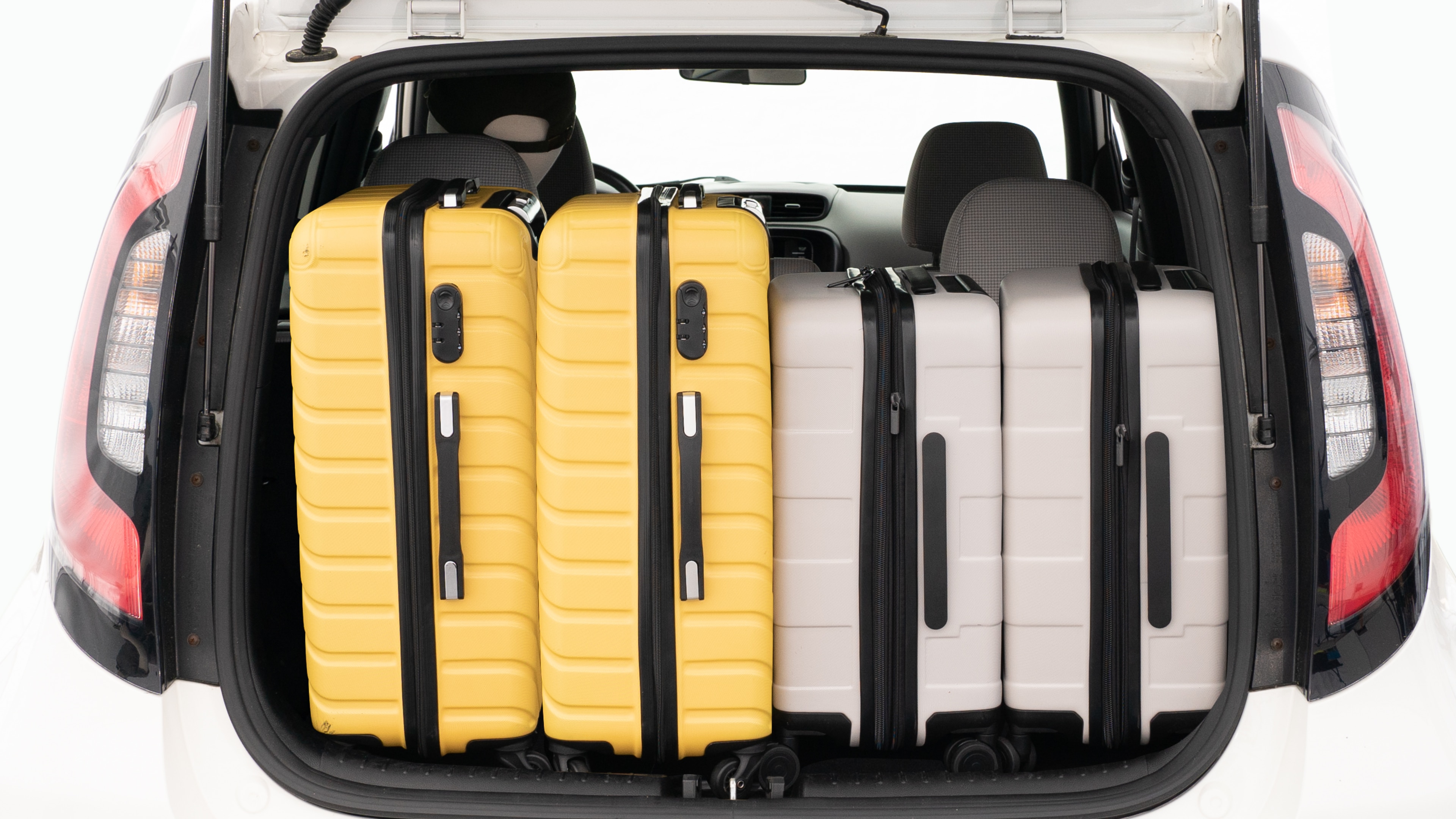 The trunk lid is open, showing a full view of the trunk space. Two large and two small suitcases are placed on there side.