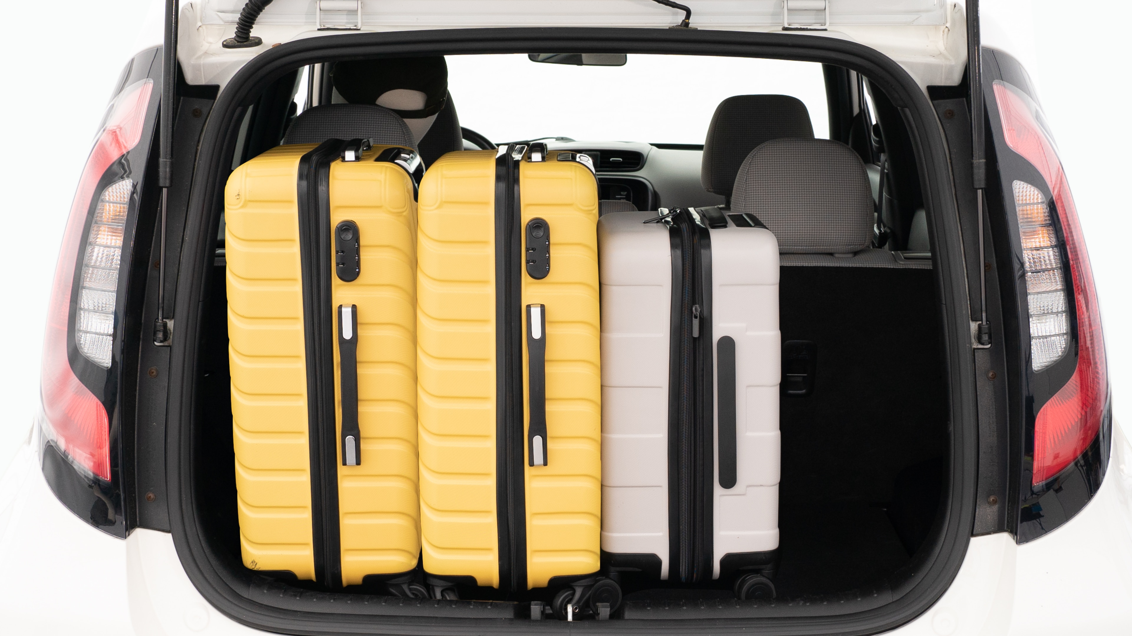 The trunk lid is open, showing a full view of the trunk space. Two large and two small suitcases are placed on there side.