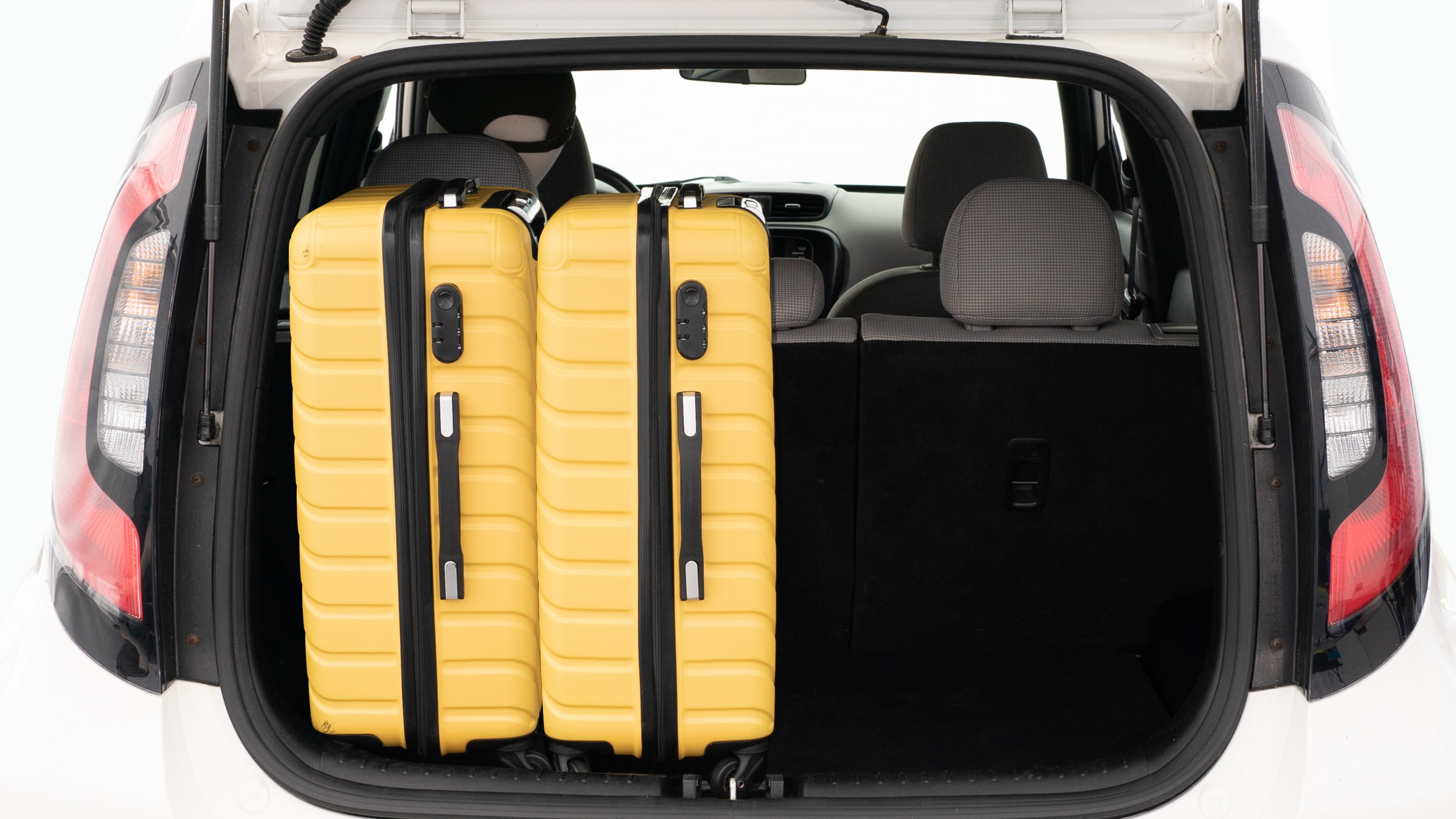 The trunk lid is open, showing a full view of the trunk space. Two large and two small suitcases are placed on there side.