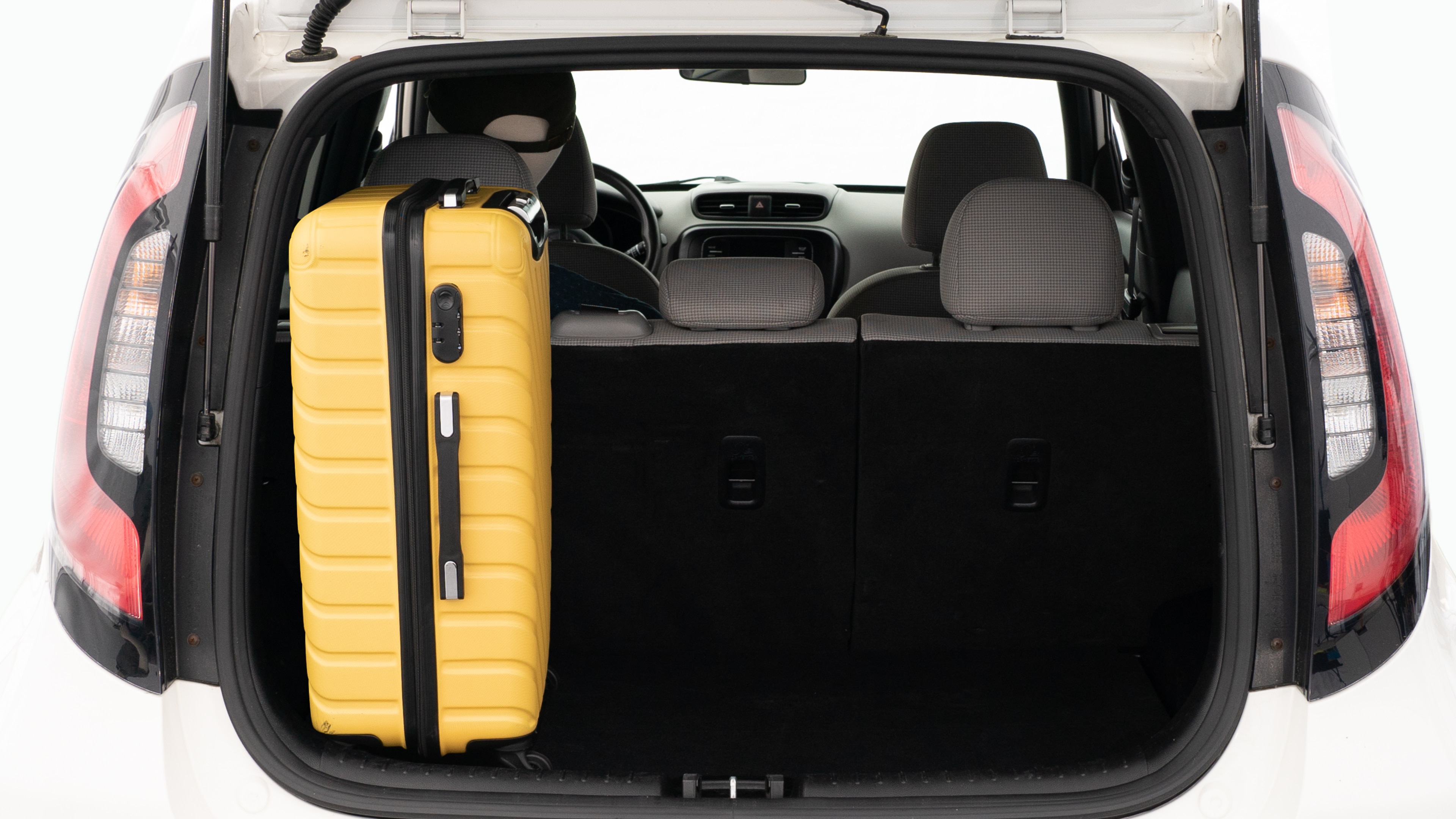 The trunk lid is open, showing a full view of the trunk space. Two large and two small suitcases are placed on there side.