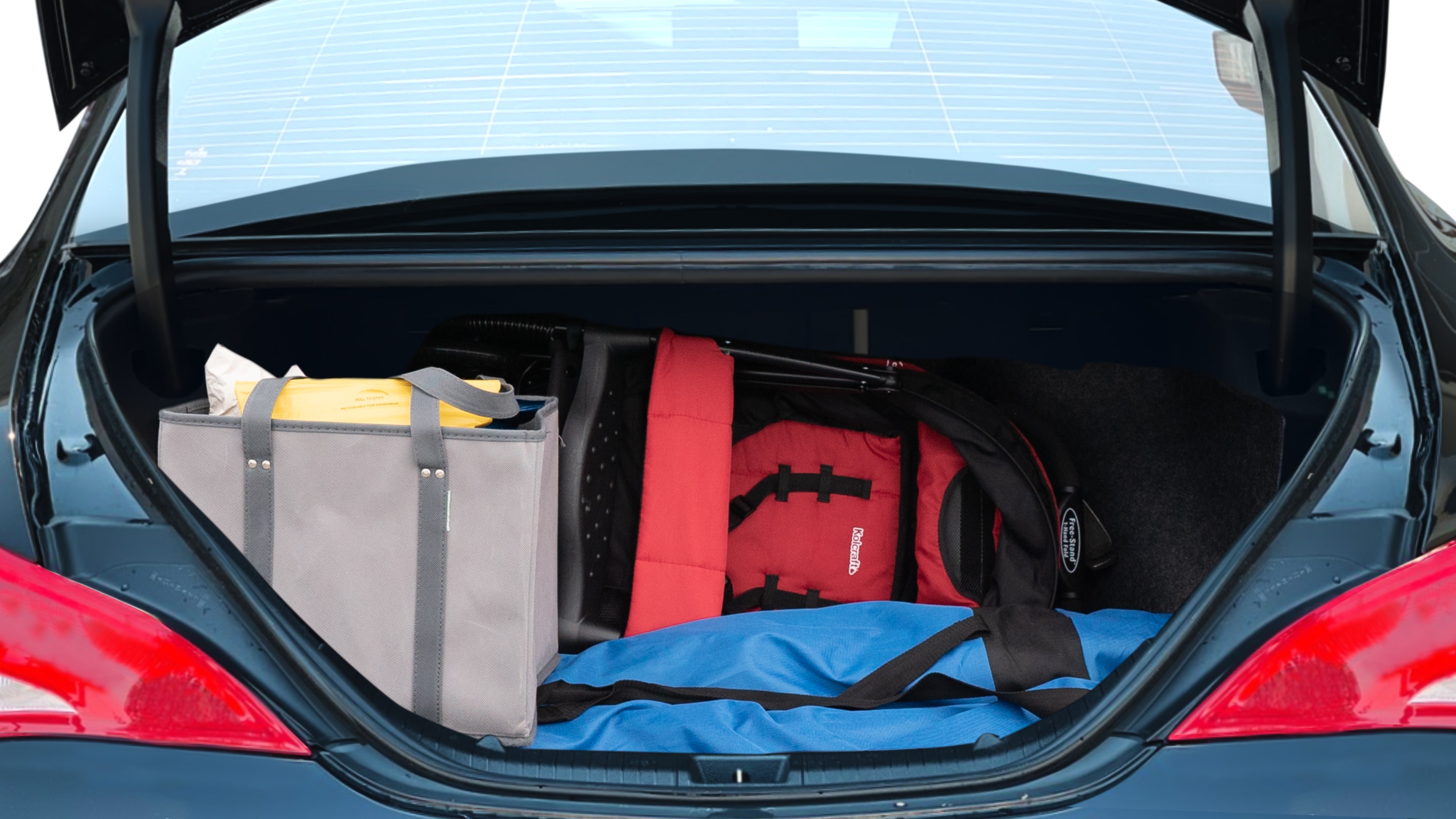 The trunk lid is open showing full view of the trunk. A baby stroller, three grocery carriers, two camping chairs in the carrying bag, and a set of golf clubs are placed inside.