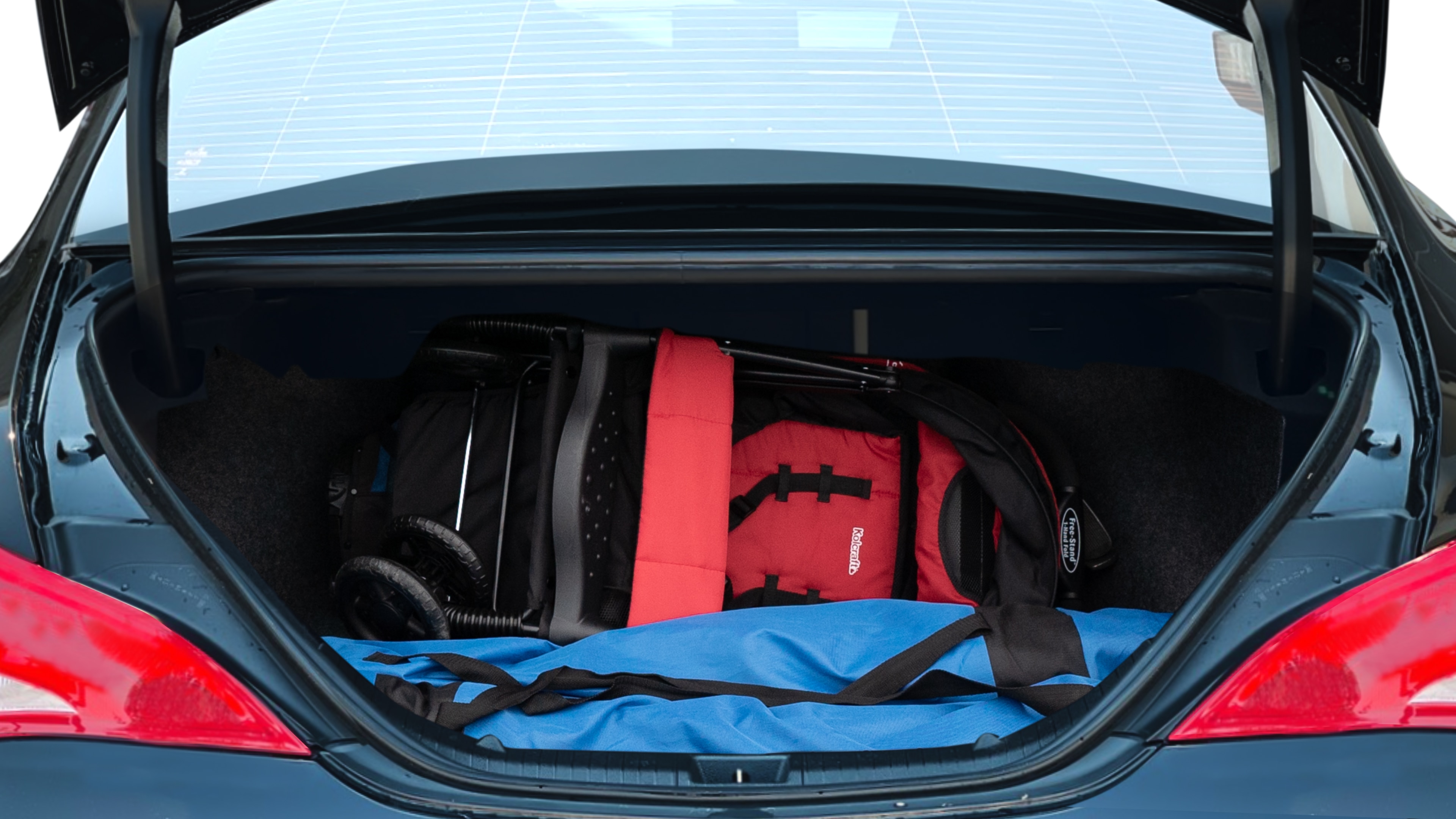 The trunk lid is open showing full view of the trunk. A baby stroller, three grocery carriers, two camping chairs in the carrying bag, and a set of golf clubs are placed inside.