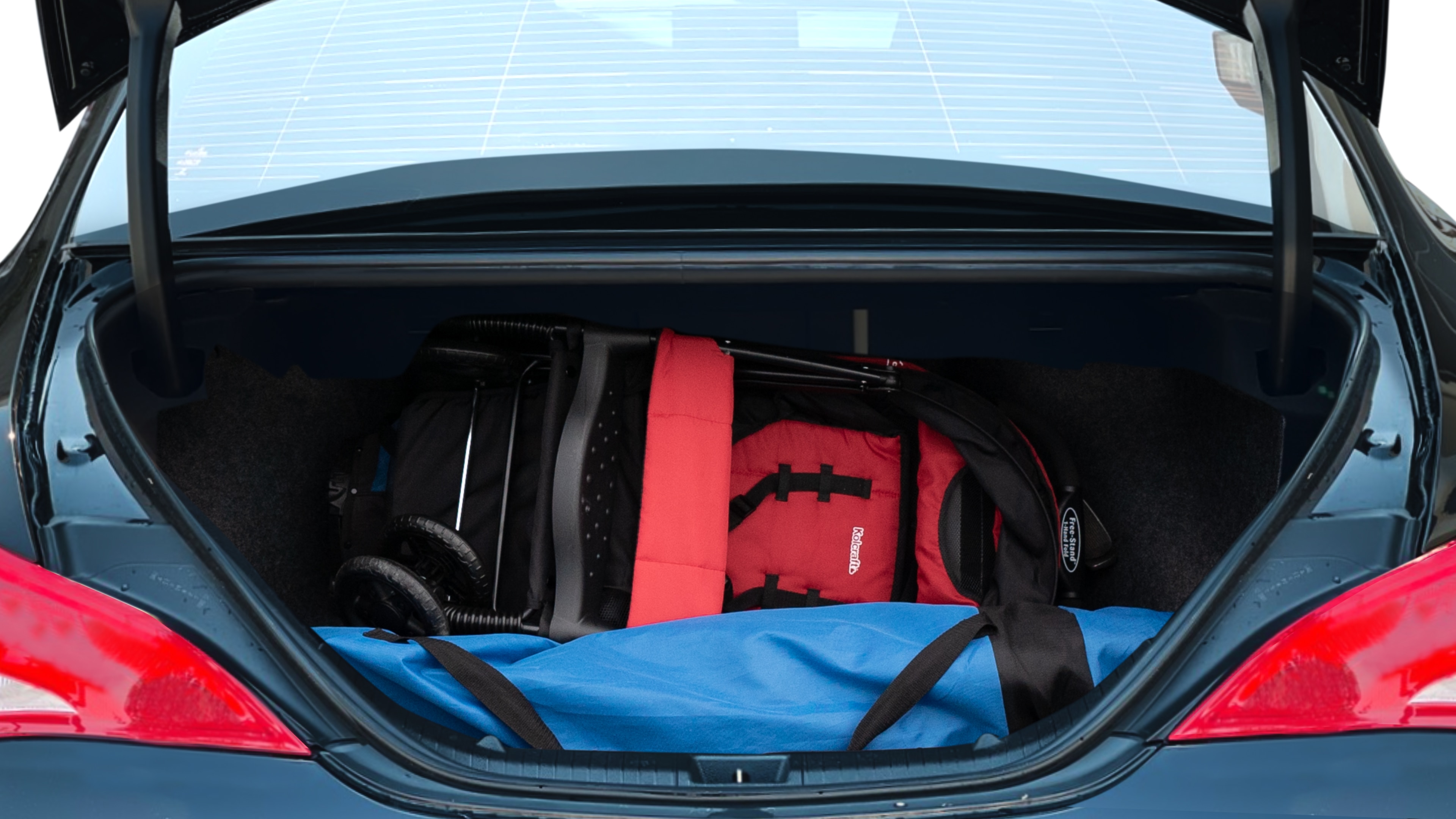 The trunk lid is open showing full view of the trunk. A baby stroller, three grocery carriers, two camping chairs in the carrying bag, and a set of golf clubs are placed inside.