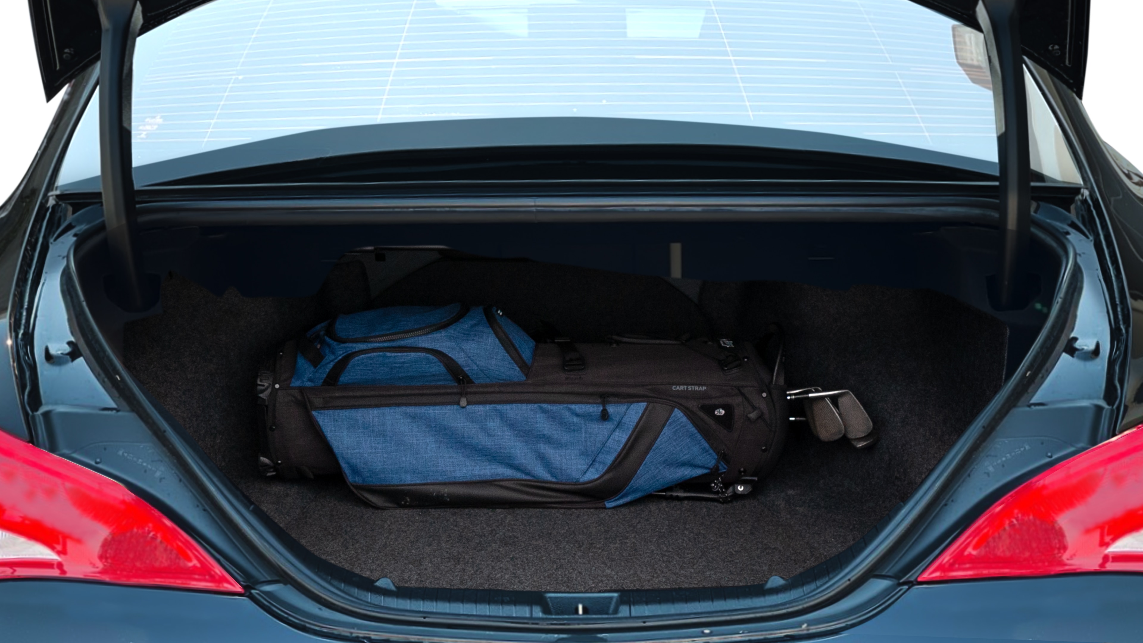 The trunk lid is open showing full view of the trunk. A baby stroller, three grocery carriers, two camping chairs in the carrying bag, and a set of golf clubs are placed inside.