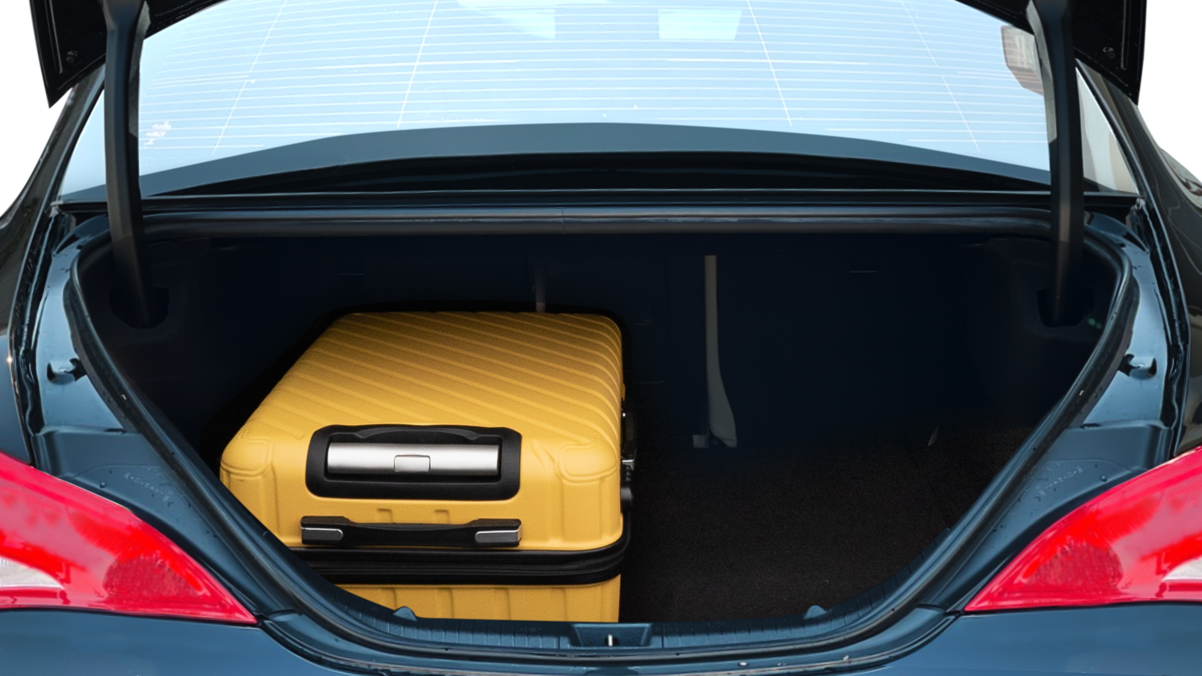 The trunk lid is open, showing full view of the trunk space. One large and two medium suitcases are placed inside.