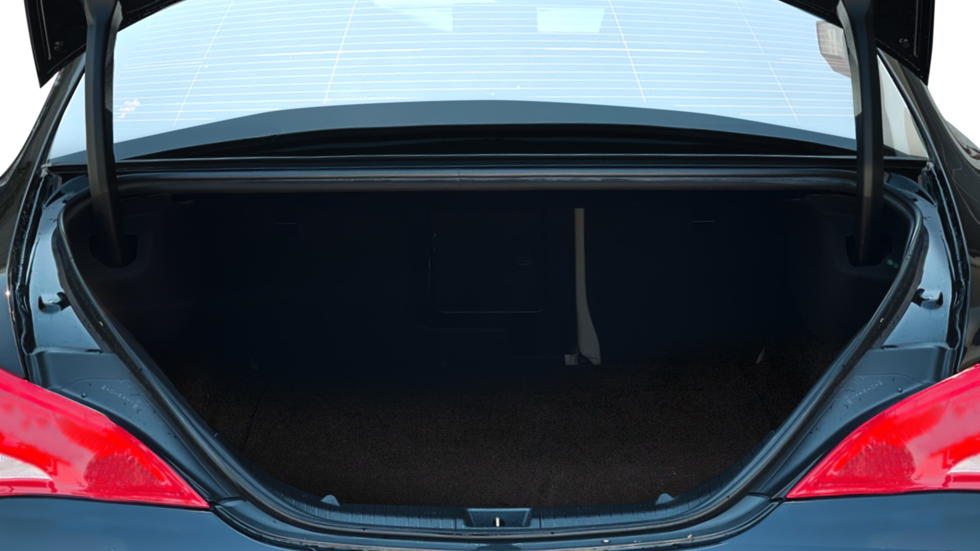 The trunk lid is open, showing full view of the trunk space. One large and two medium suitcases are placed inside.