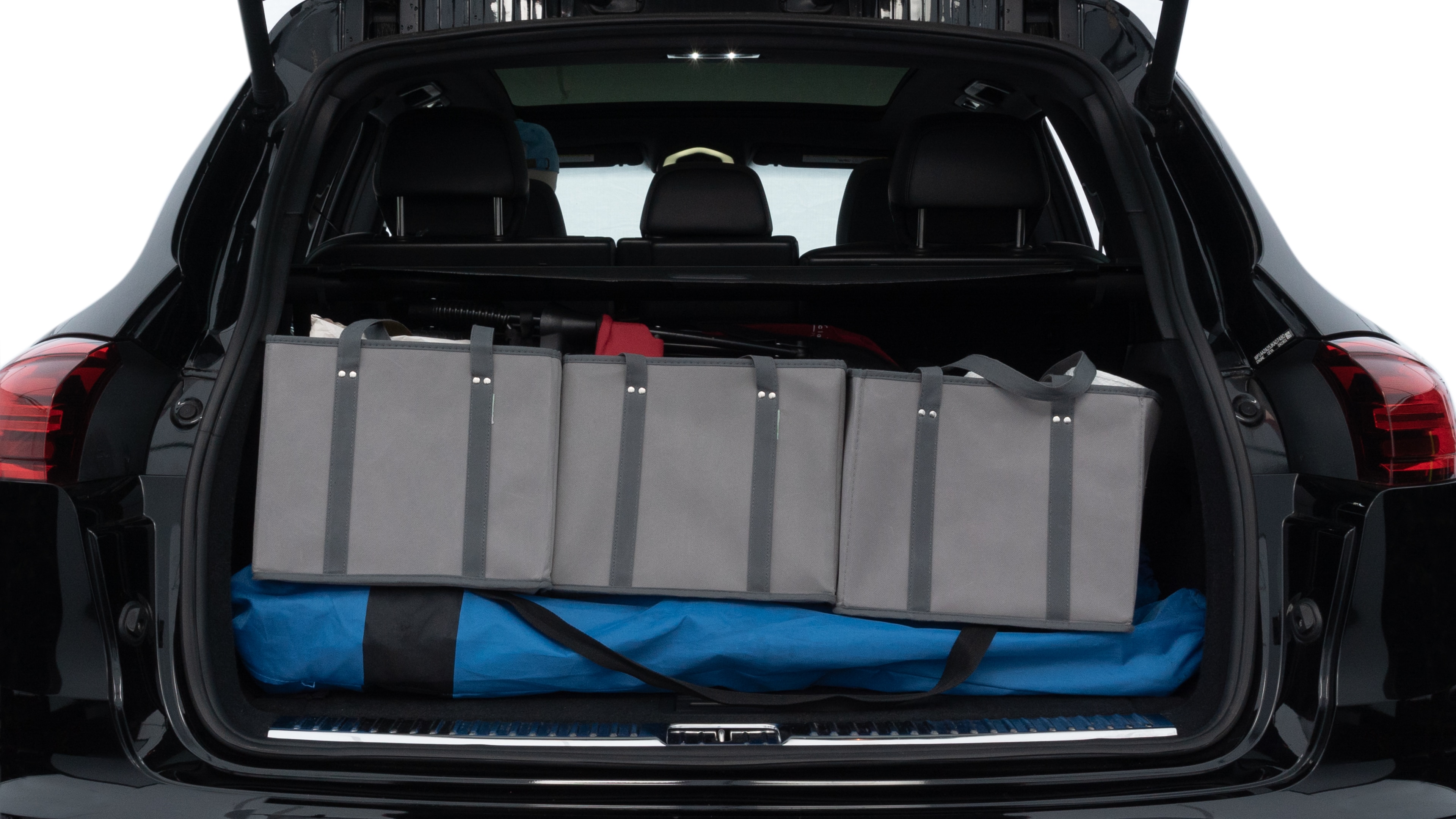 The trunk lid is open, showing full view of the trunk space. Two medium and two small suitcases are placed inside.