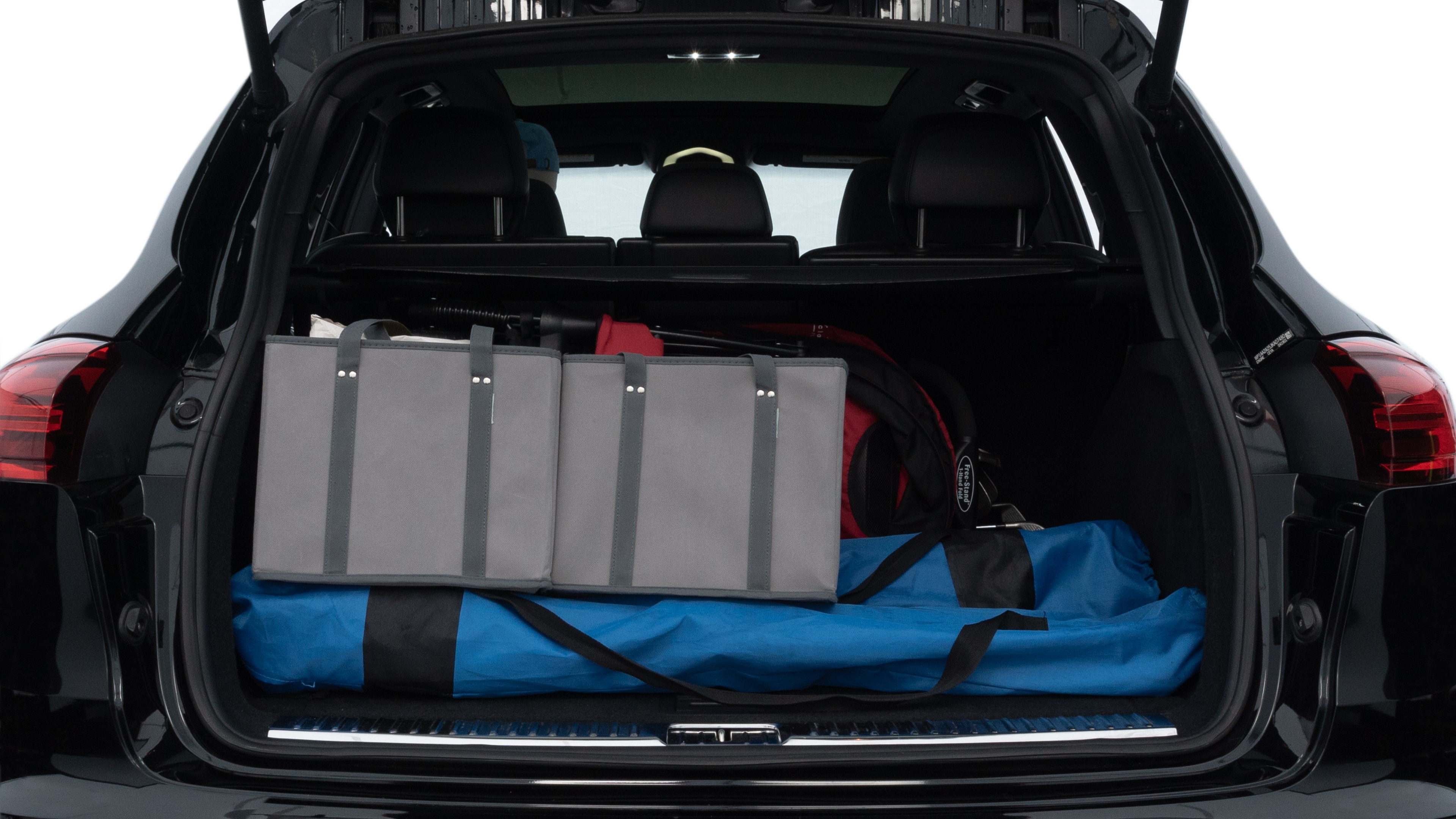 The trunk lid is open, showing full view of the trunk space. Two medium and two small suitcases are placed inside.