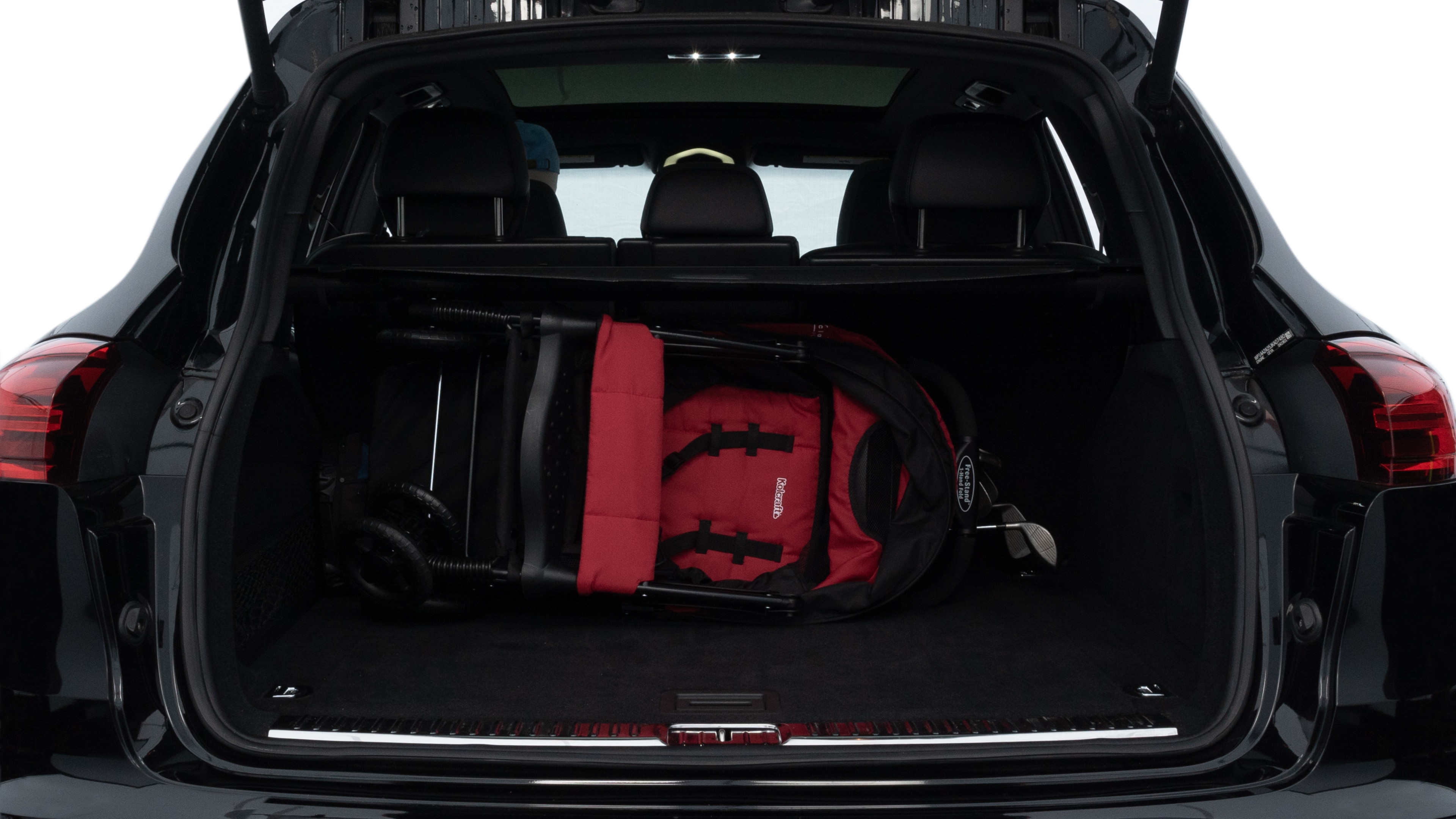 The trunk lid is open, showing full view of the trunk space. Two medium and two small suitcases are placed inside.