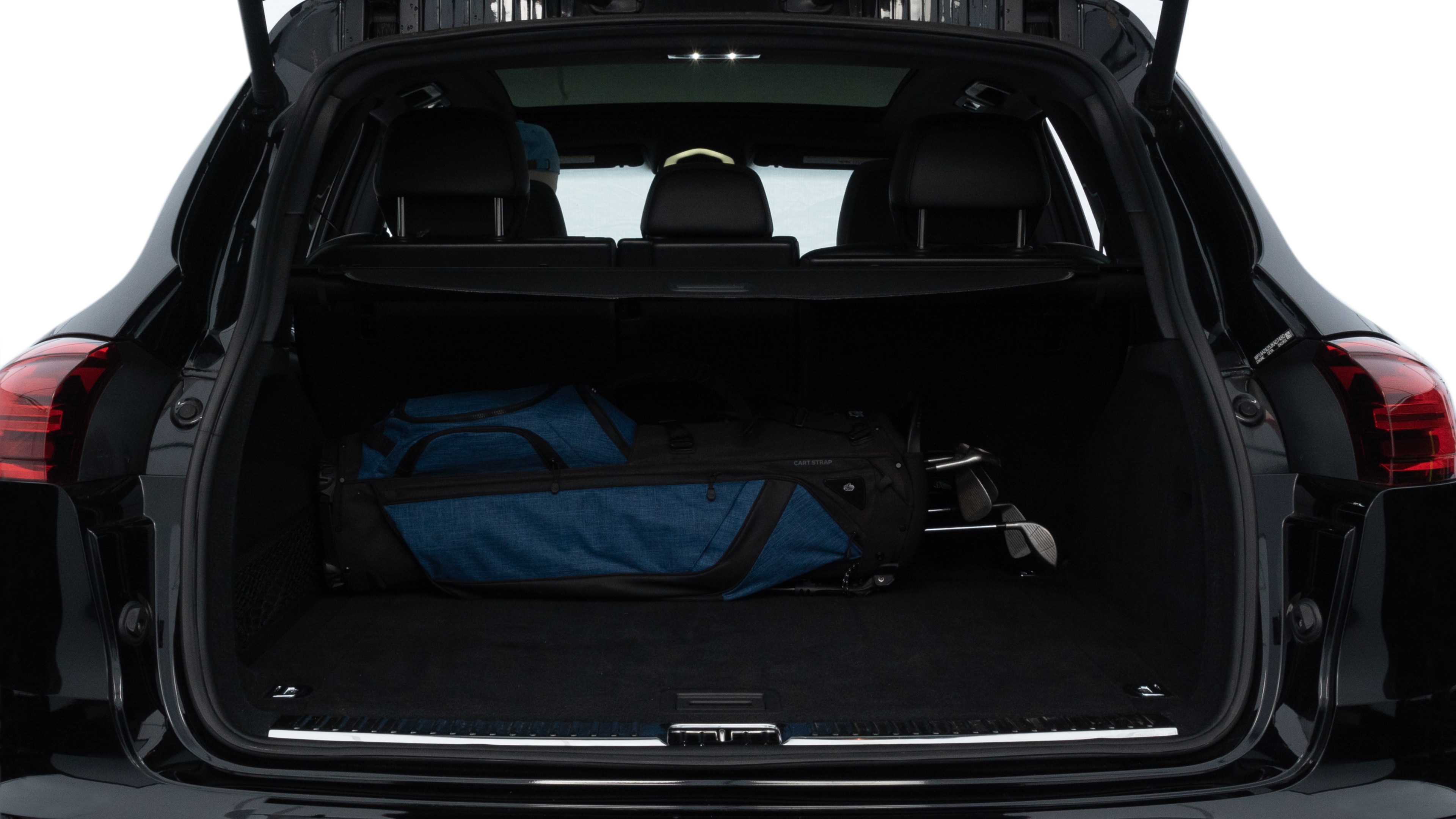 The trunk lid is open, showing full view of the trunk space. Two medium and two small suitcases are placed inside.