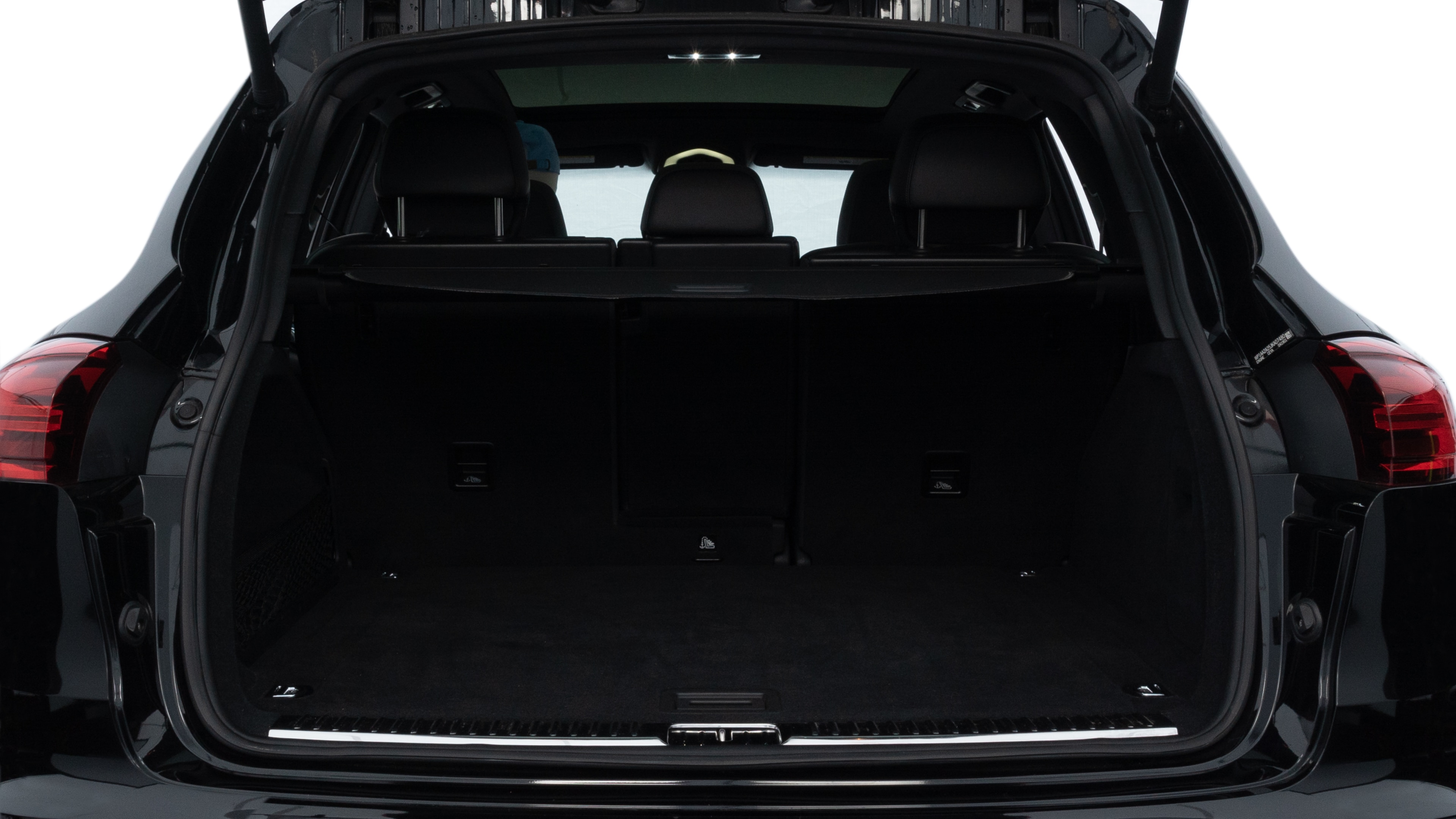 The trunk lid is open, showing full view of the trunk space. Two medium and two small suitcases are placed inside.
