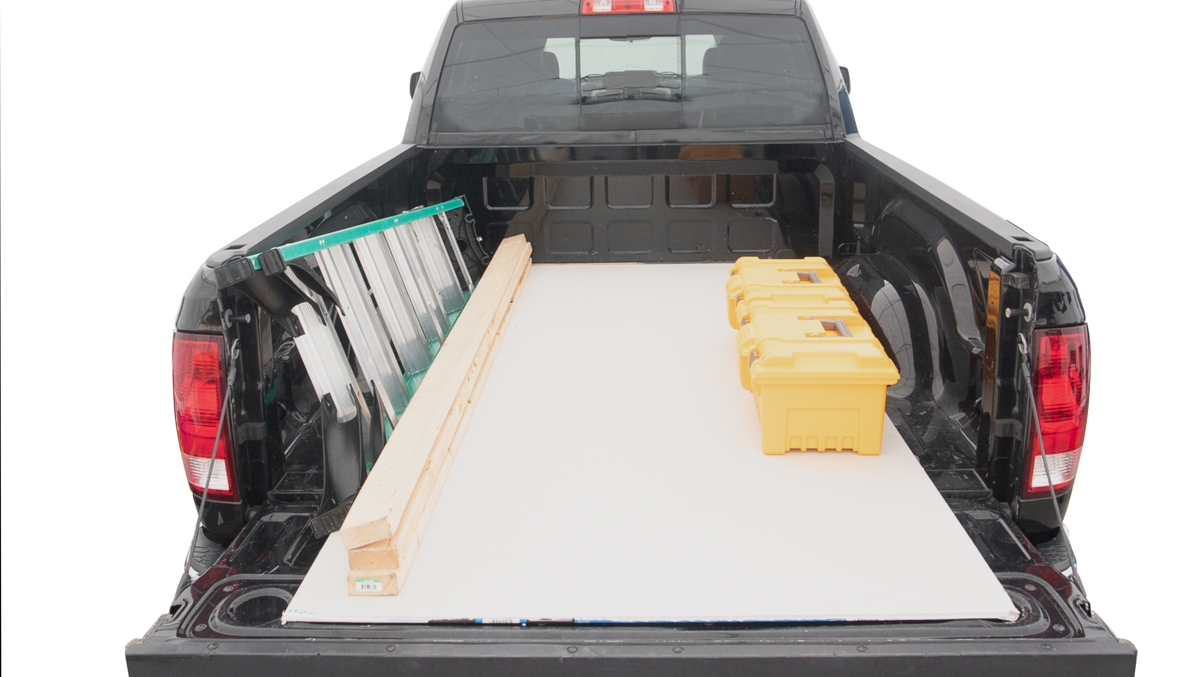 The trunk area is open giving a full view of the trunk area. A ladder, three 2 by 4 framing studs, two tool boxes and a 4 by 8 drywall sheet are placed inside. 