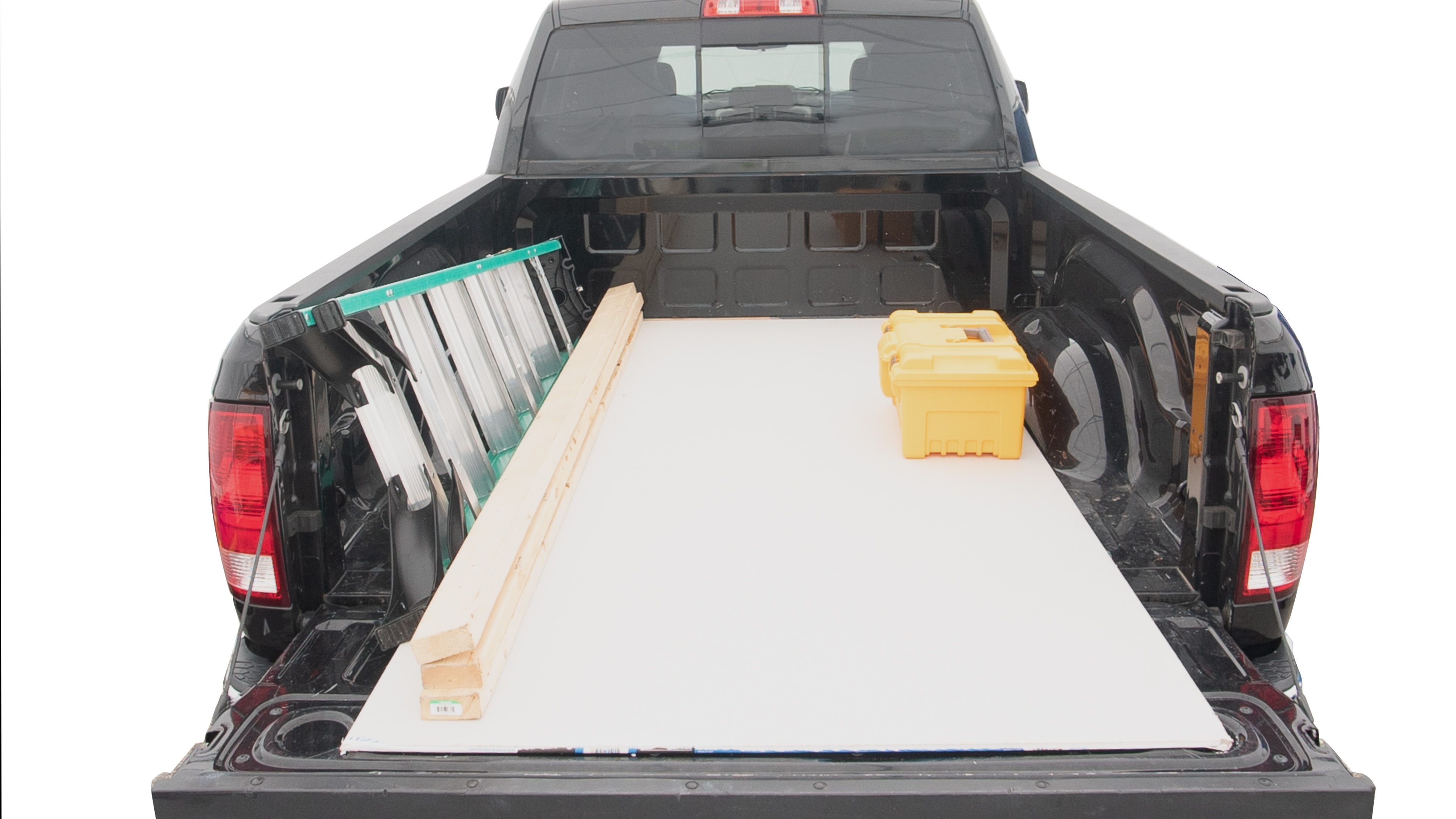 The trunk area is open giving a full view of the trunk area. A ladder, three 2 by 4 framing studs, two tool boxes and a 4 by 8 drywall sheet are placed inside. 
