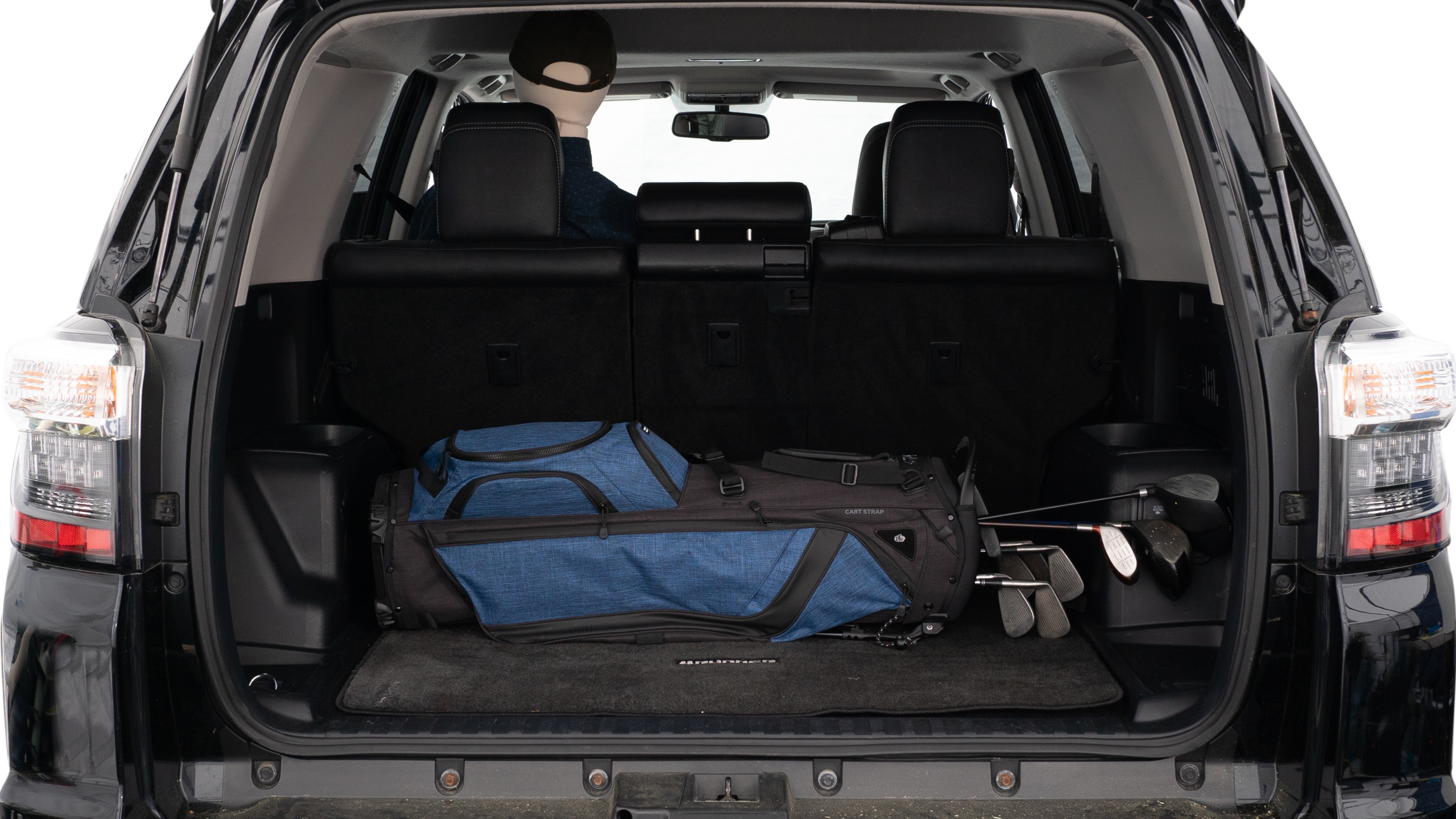 The trunk lid is open showing full view of the trunk. A baby stroller, three grocery carriers, two camping chairs in the carrying bag, and a set of golf clubs are placed inside.