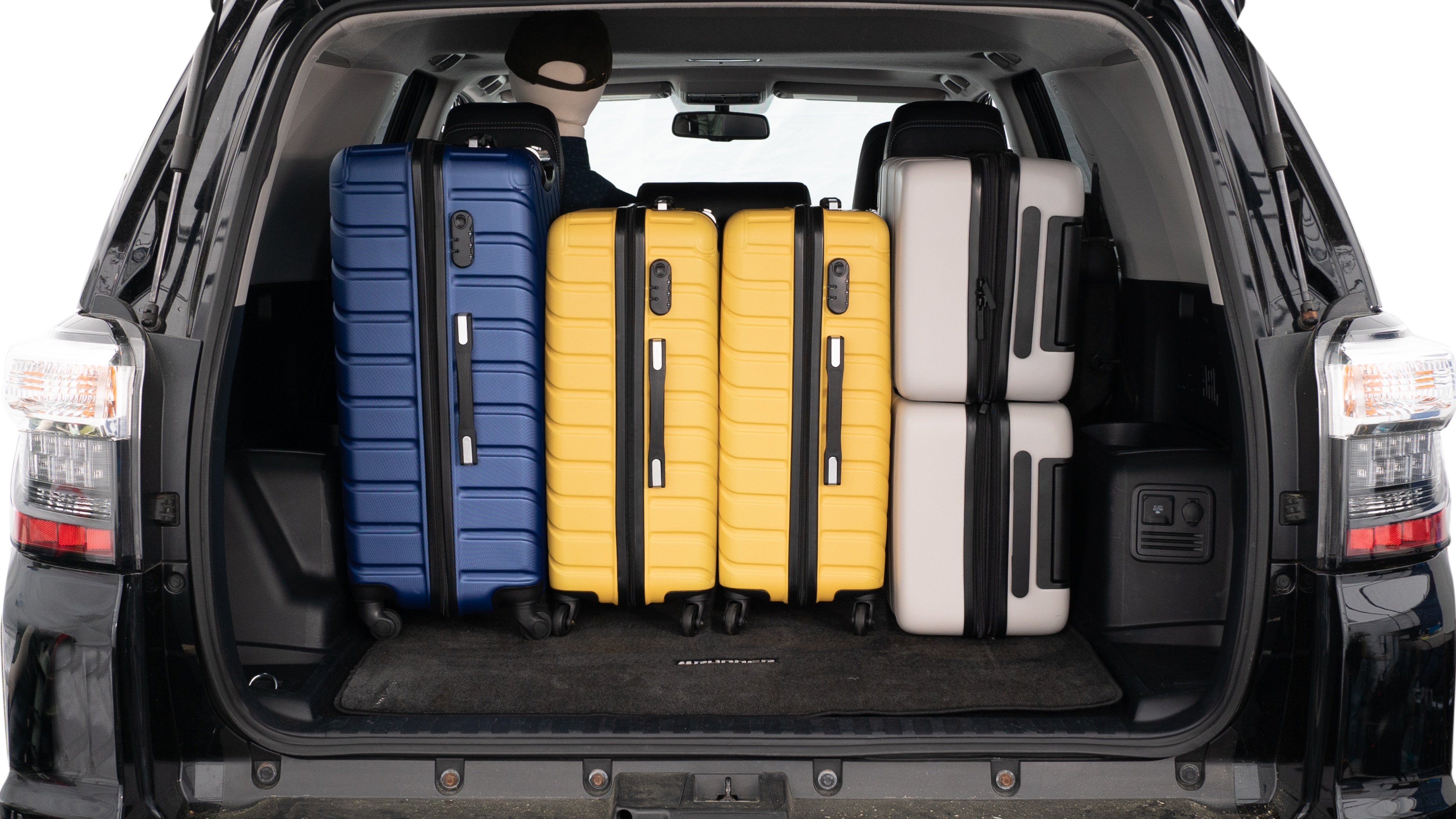 The trunk lid is open, showing a full view of the trunk space. Three large suitcases and two small suitcases are placed inside.