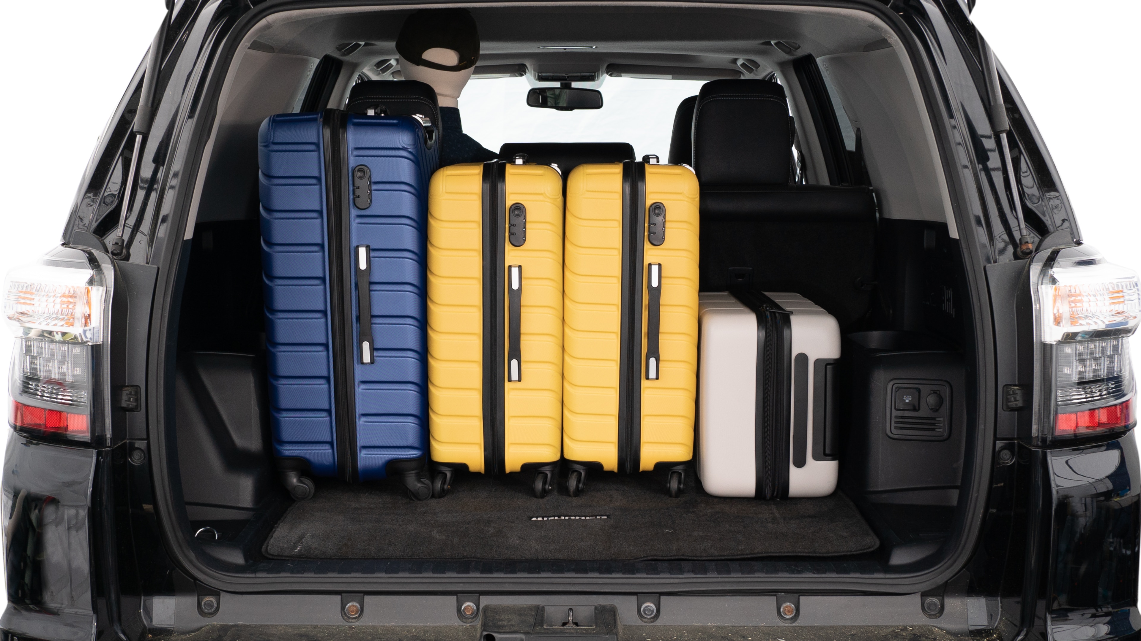 The trunk lid is open, showing a full view of the trunk space. Three large suitcases and two small suitcases are placed inside.