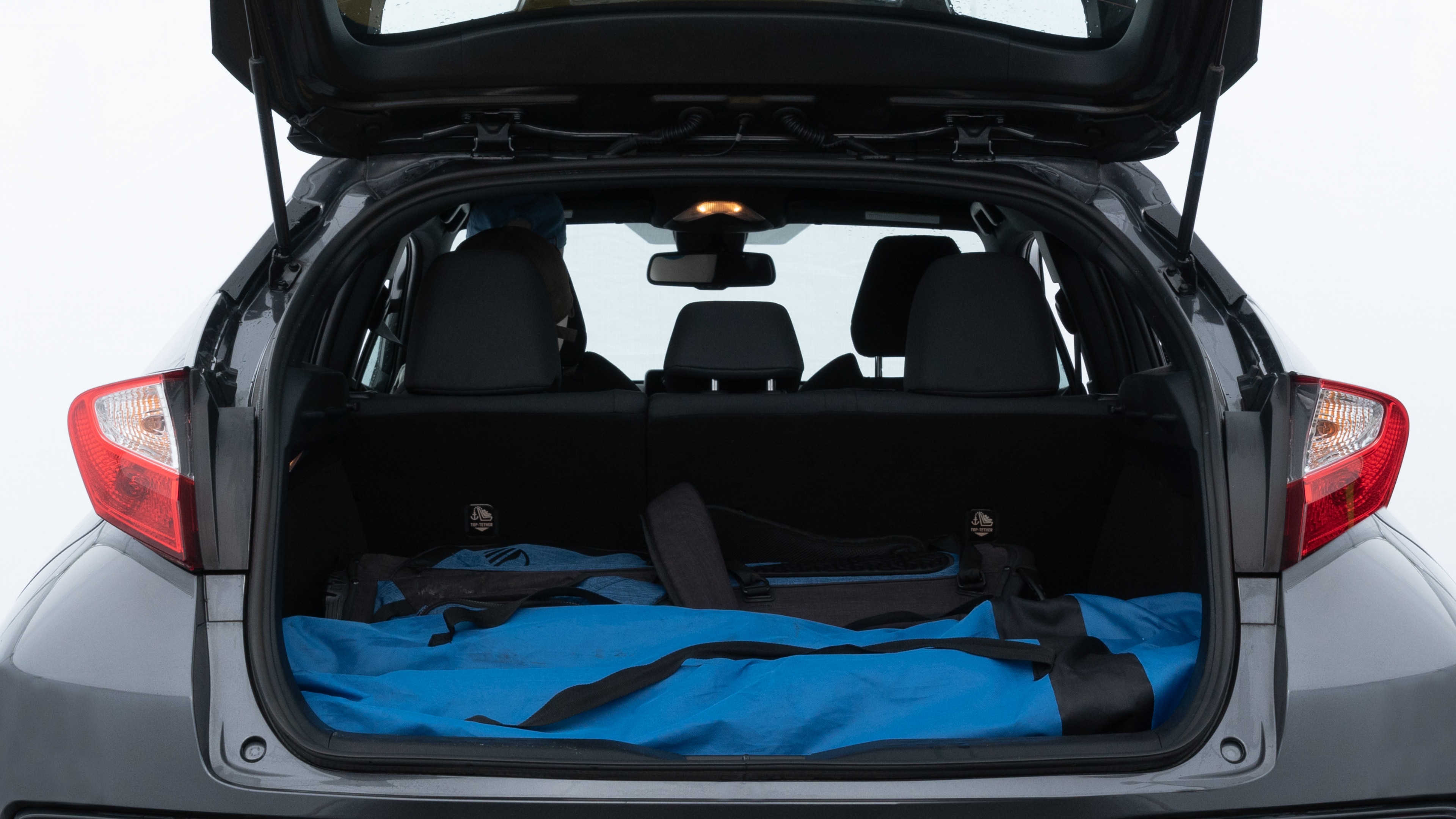 The trunk lid is open showing full view of the trunk. A baby stroller, three grocery carriers, two camping chairs in the carrying bag, and a set of golf clubs are placed inside.
