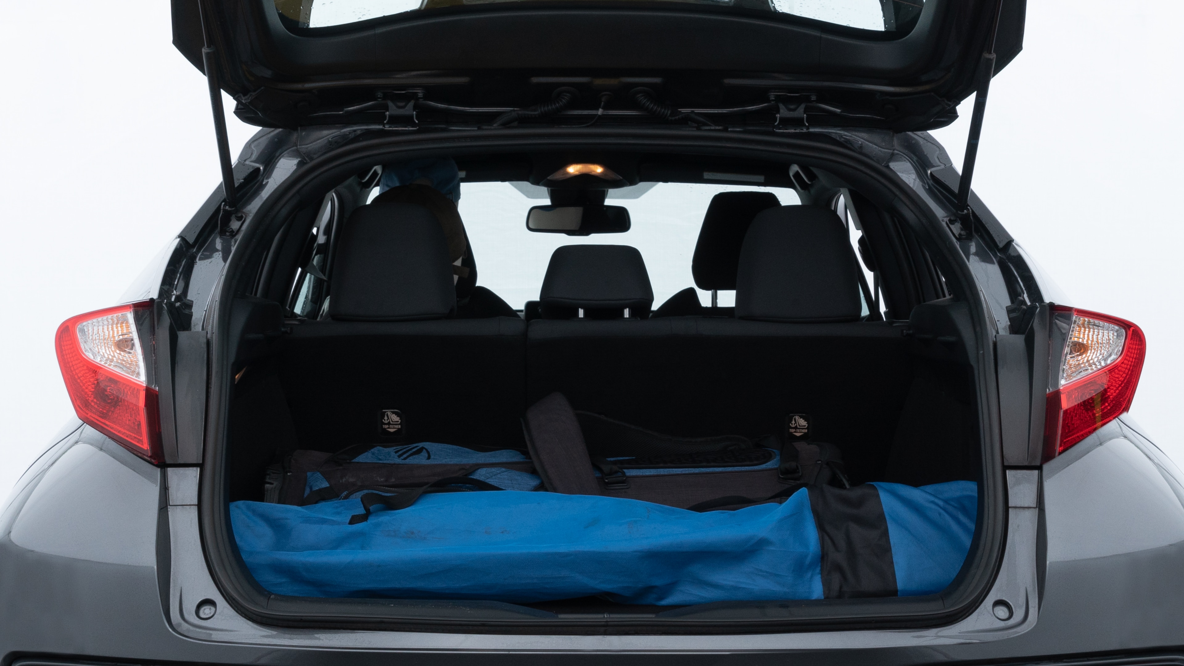 The trunk lid is open showing full view of the trunk. A baby stroller, three grocery carriers, two camping chairs in the carrying bag, and a set of golf clubs are placed inside.
