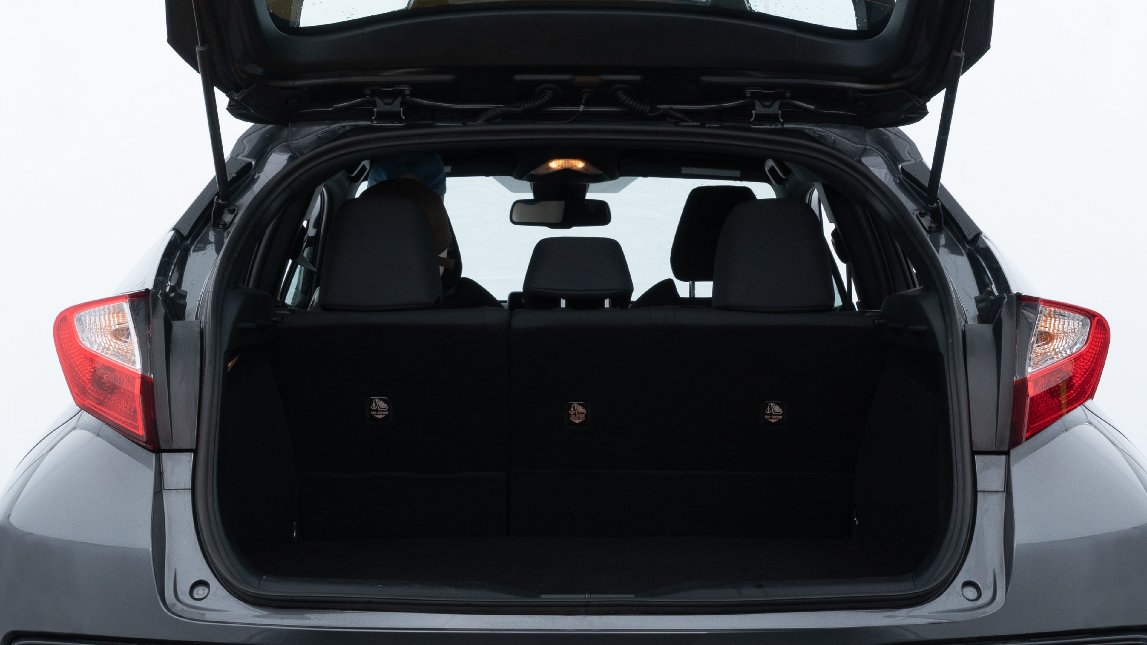 The trunk lid is open showing full view of the trunk. A baby stroller, three grocery carriers, two camping chairs in the carrying bag, and a set of golf clubs are placed inside.