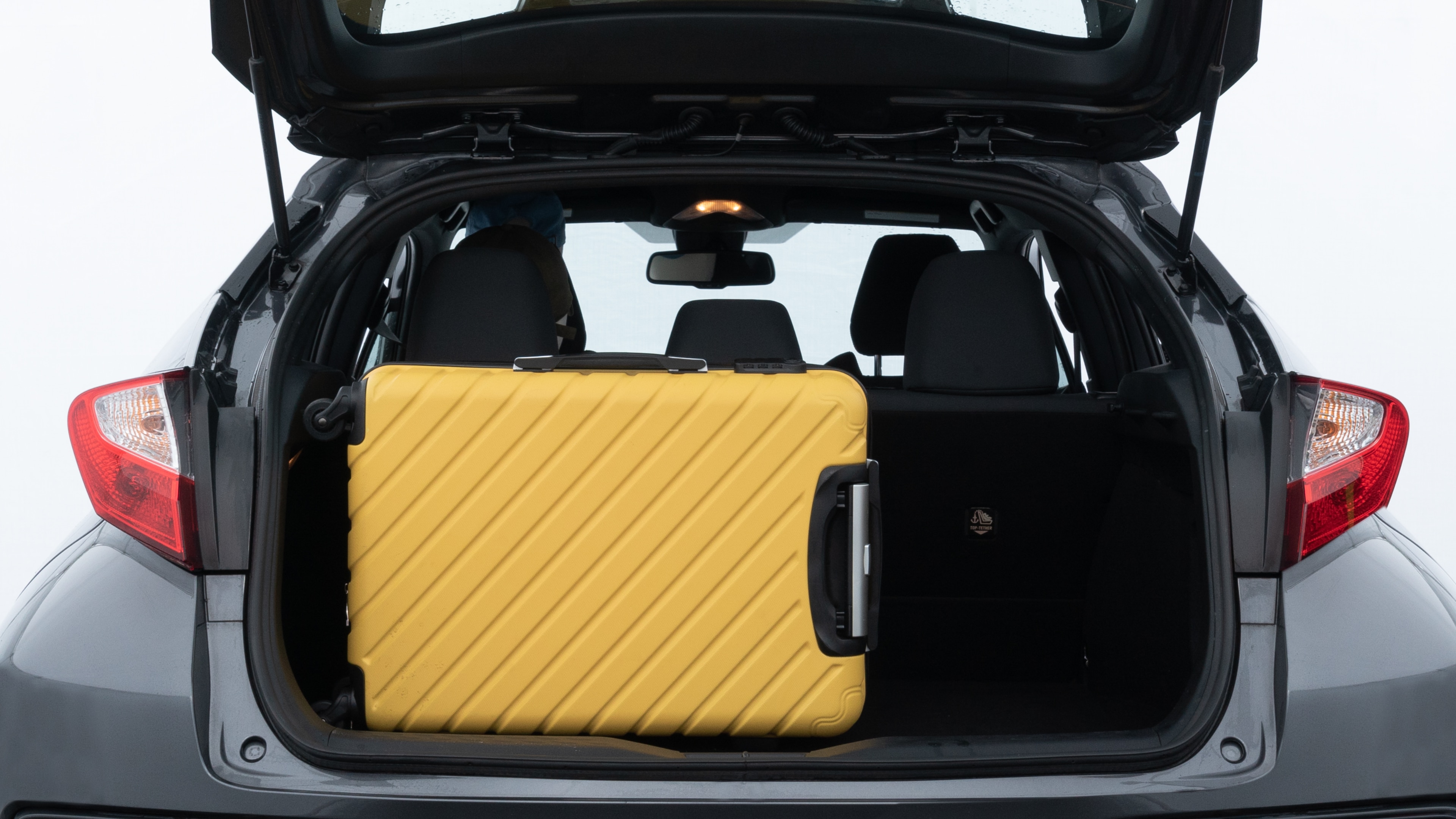 The trunk lid is open, showing full view of the trunk space. Two medium and one small suitcases are placed inside.