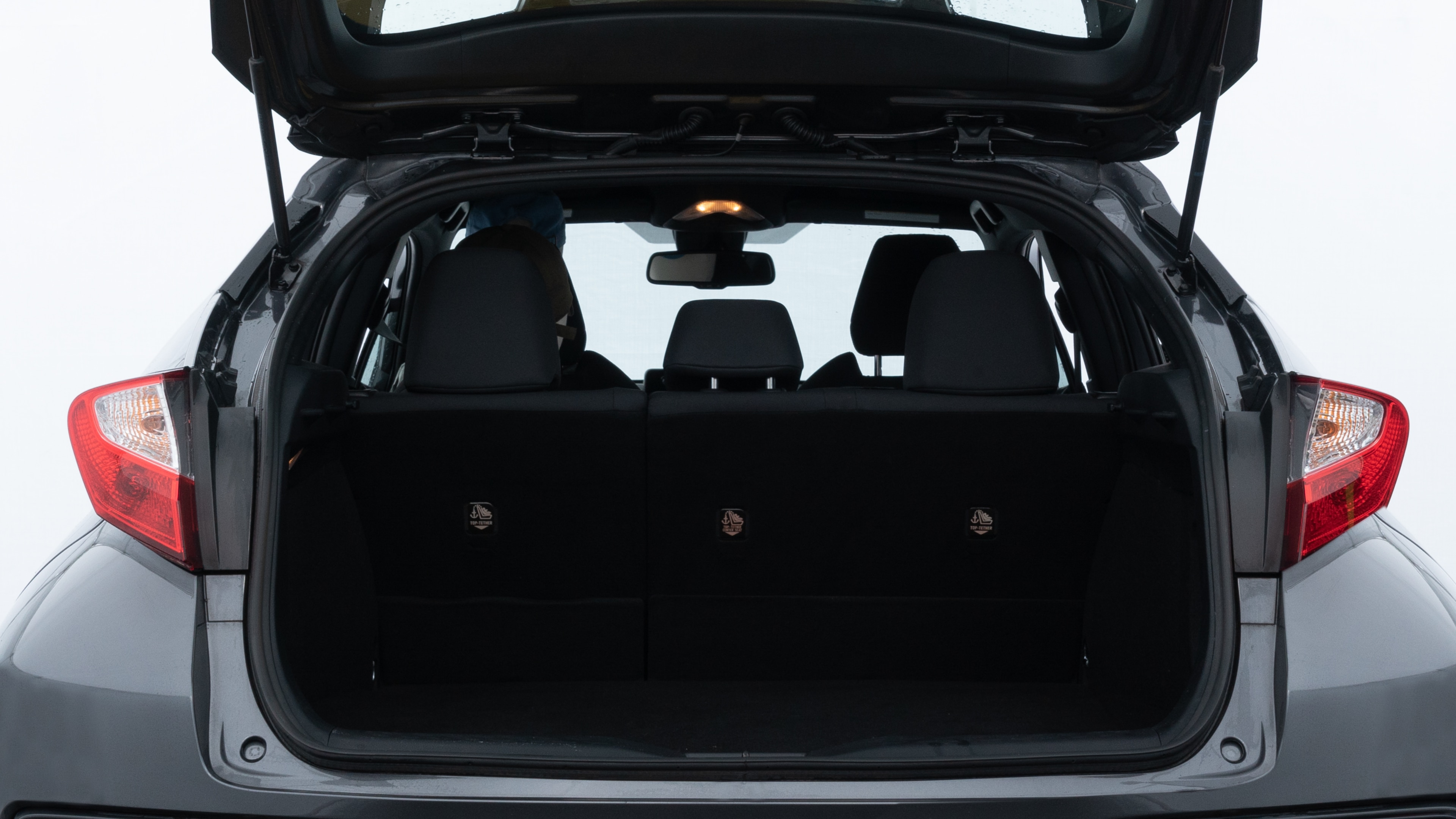 The trunk lid is open, showing full view of the trunk space. Two medium and one small suitcases are placed inside.