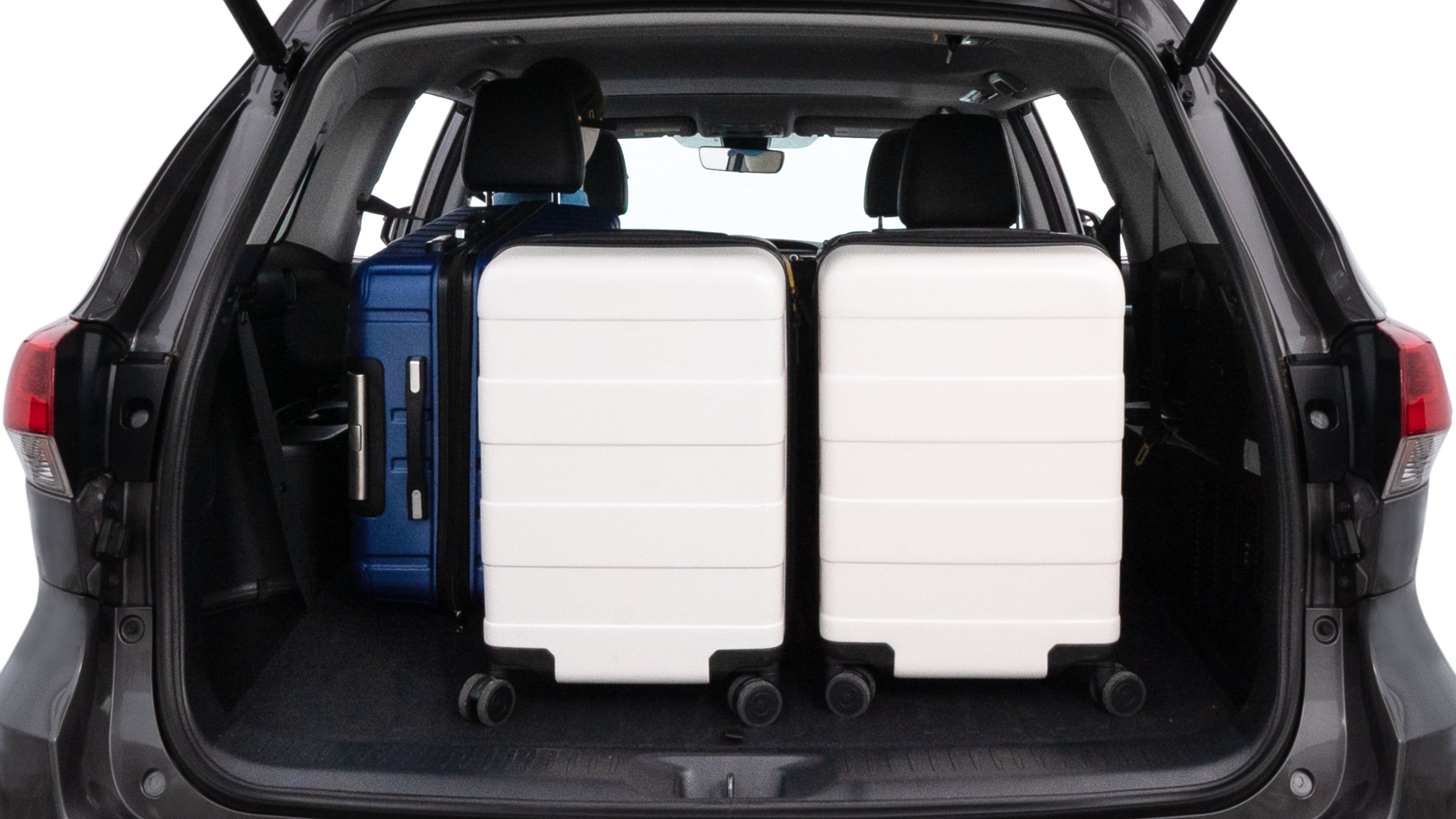 The trunk lid is open, showing full view of the trunk space. One large suitcase, two medium suitcases, and two small suitcases are placed inside.