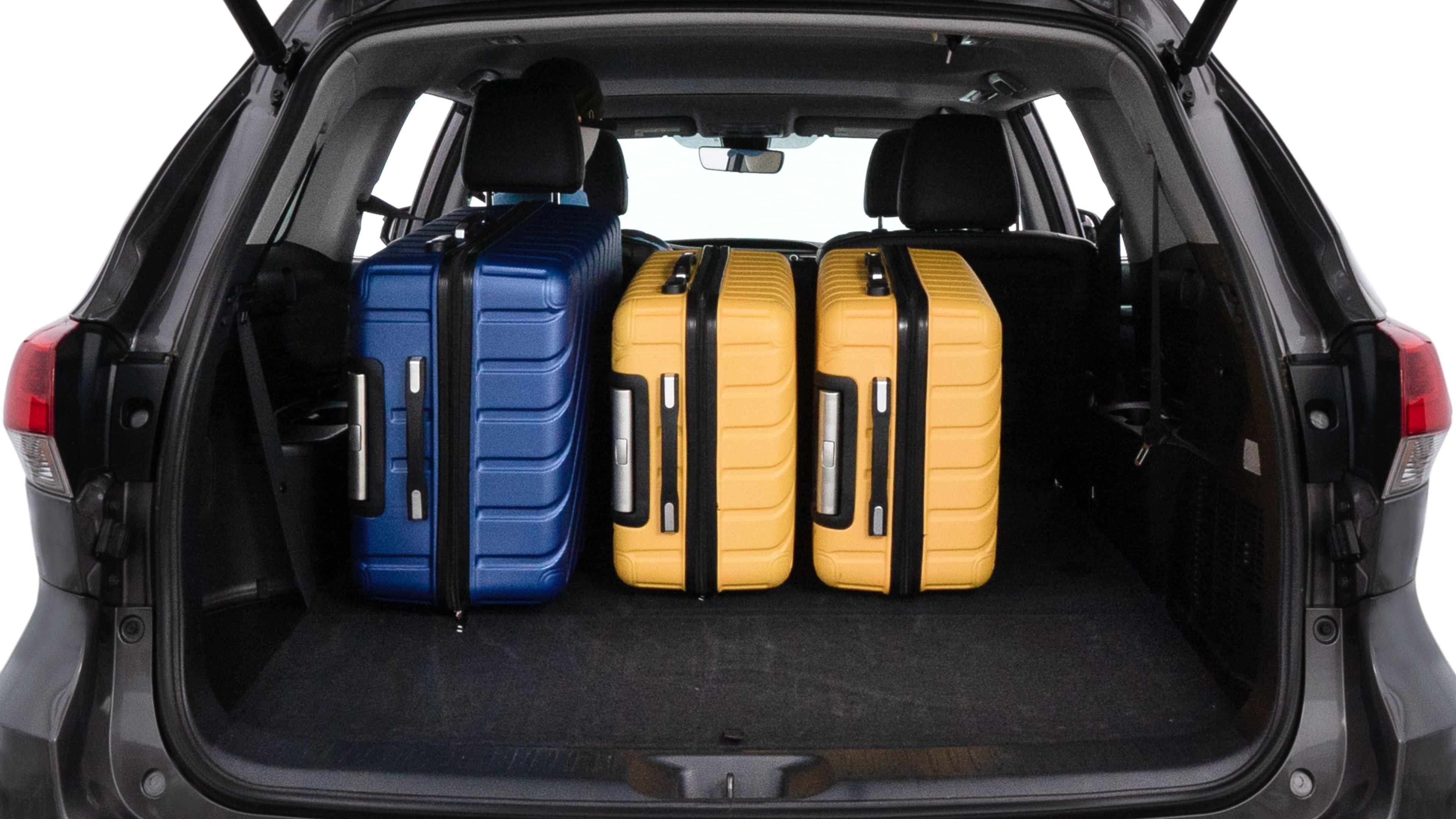 The trunk lid is open, showing full view of the trunk space. One large suitcase, two medium suitcases, and two small suitcases are placed inside.