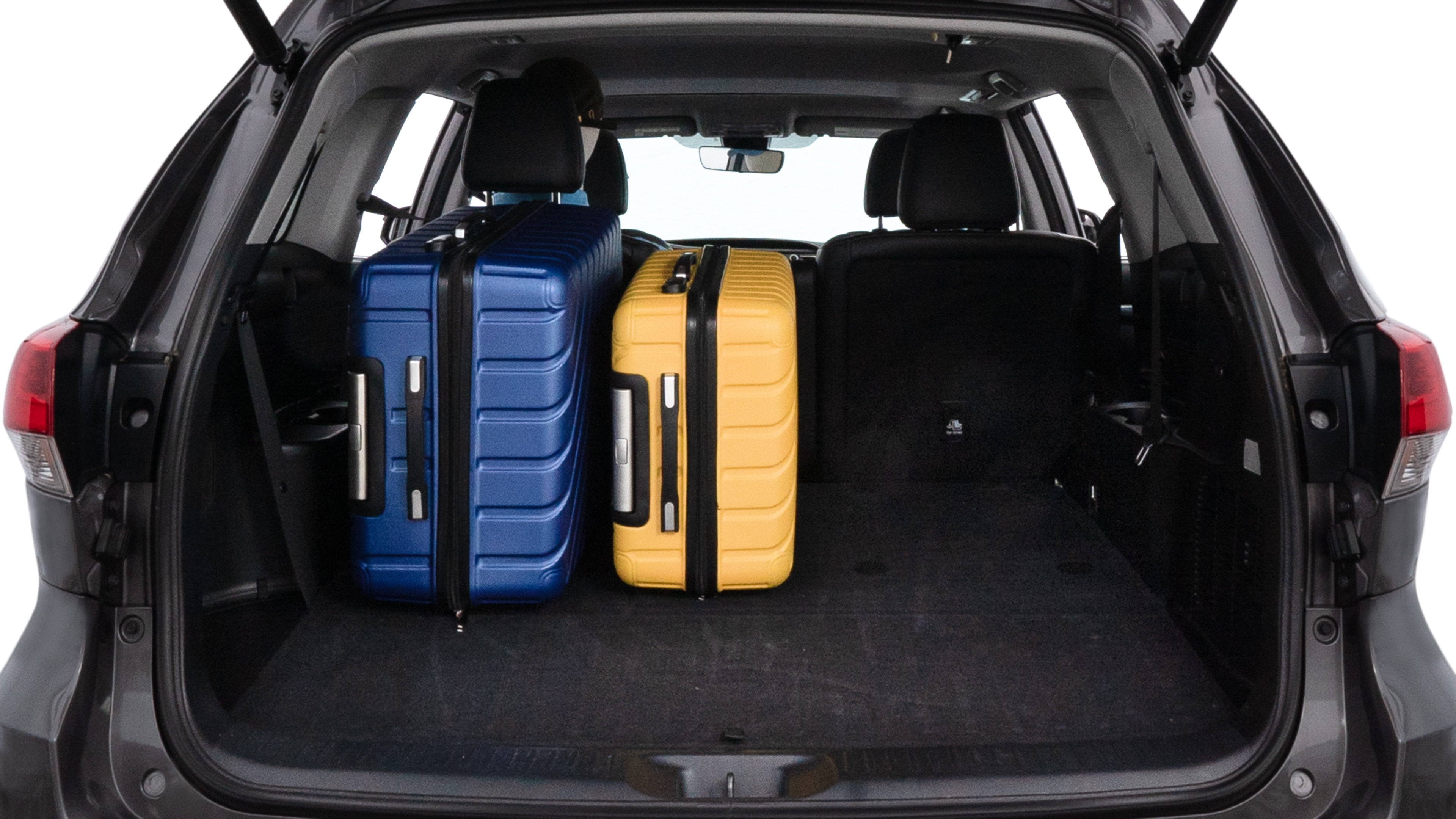 The trunk lid is open, showing full view of the trunk space. One large suitcase, two medium suitcases, and two small suitcases are placed inside.