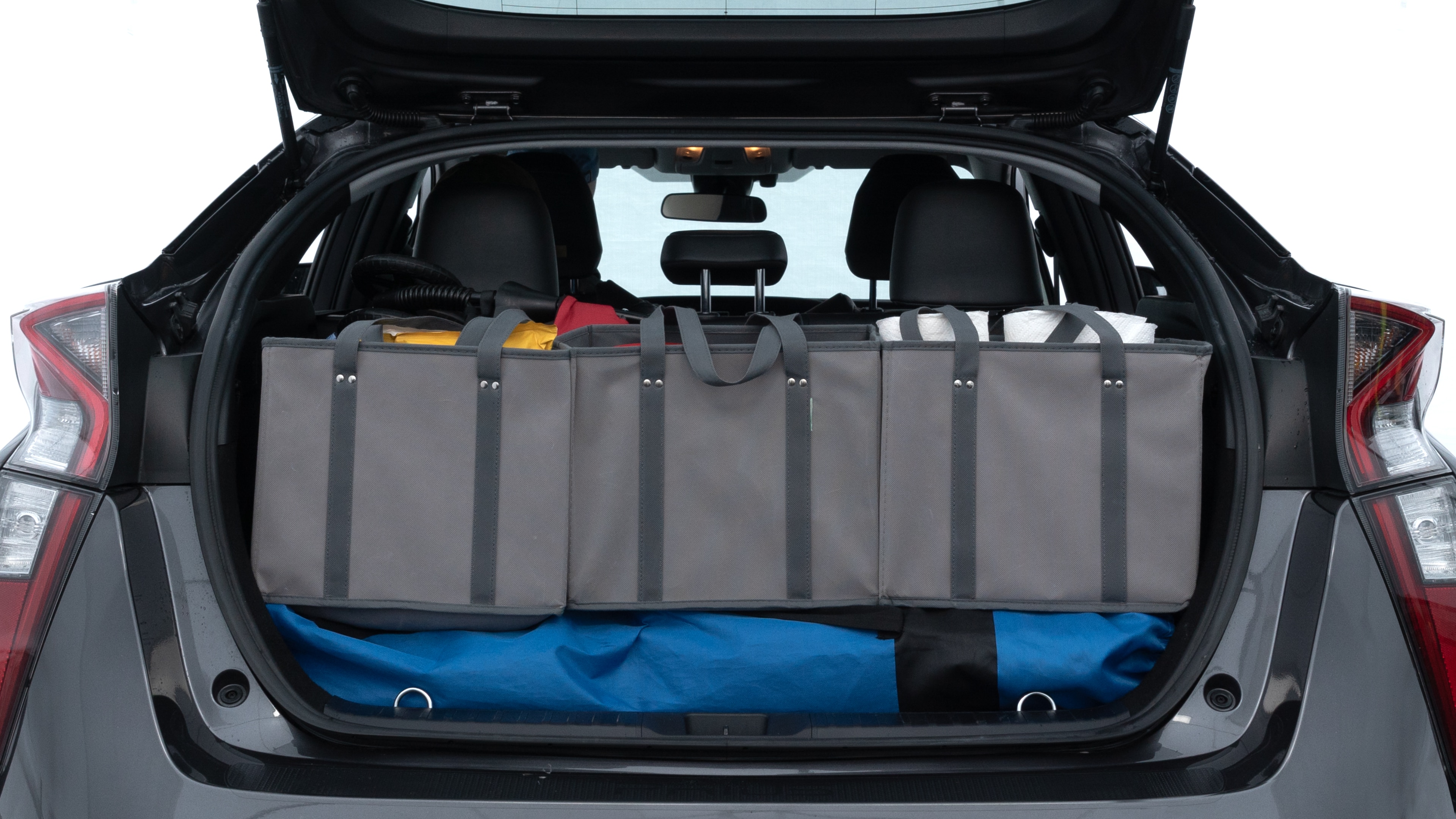 The trunk lid is open showing full view of the trunk. A baby stroller, three grocery carriers, two camping chairs in the carrying bag, and a set of golf clubs are placed inside.