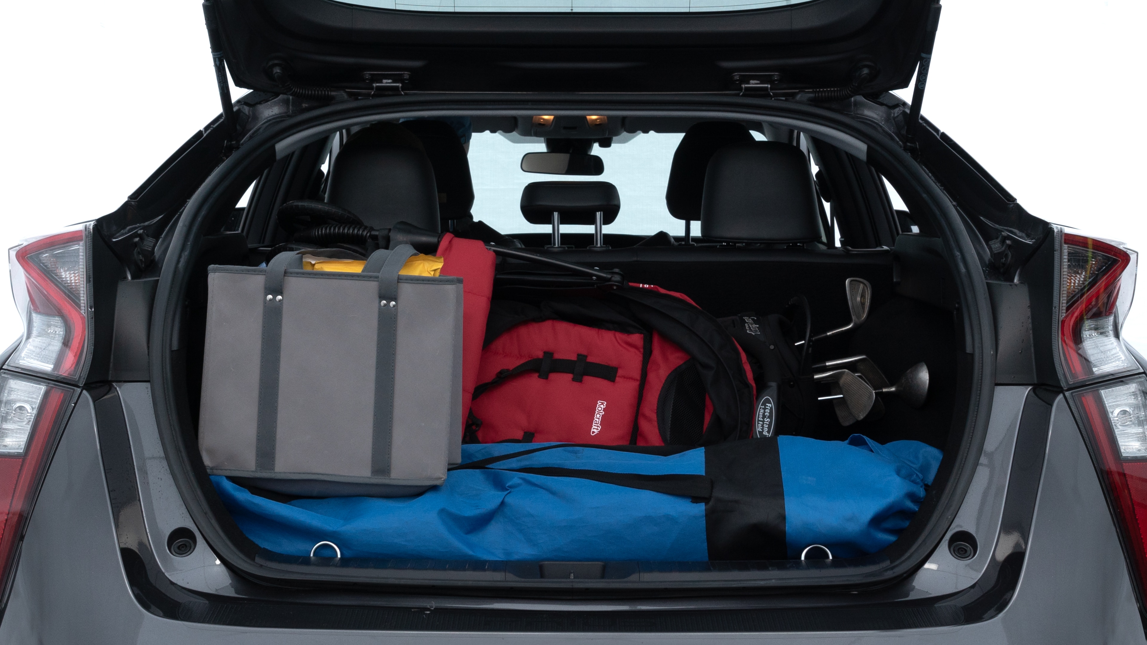 The trunk lid is open showing full view of the trunk. A baby stroller, three grocery carriers, two camping chairs in the carrying bag, and a set of golf clubs are placed inside.