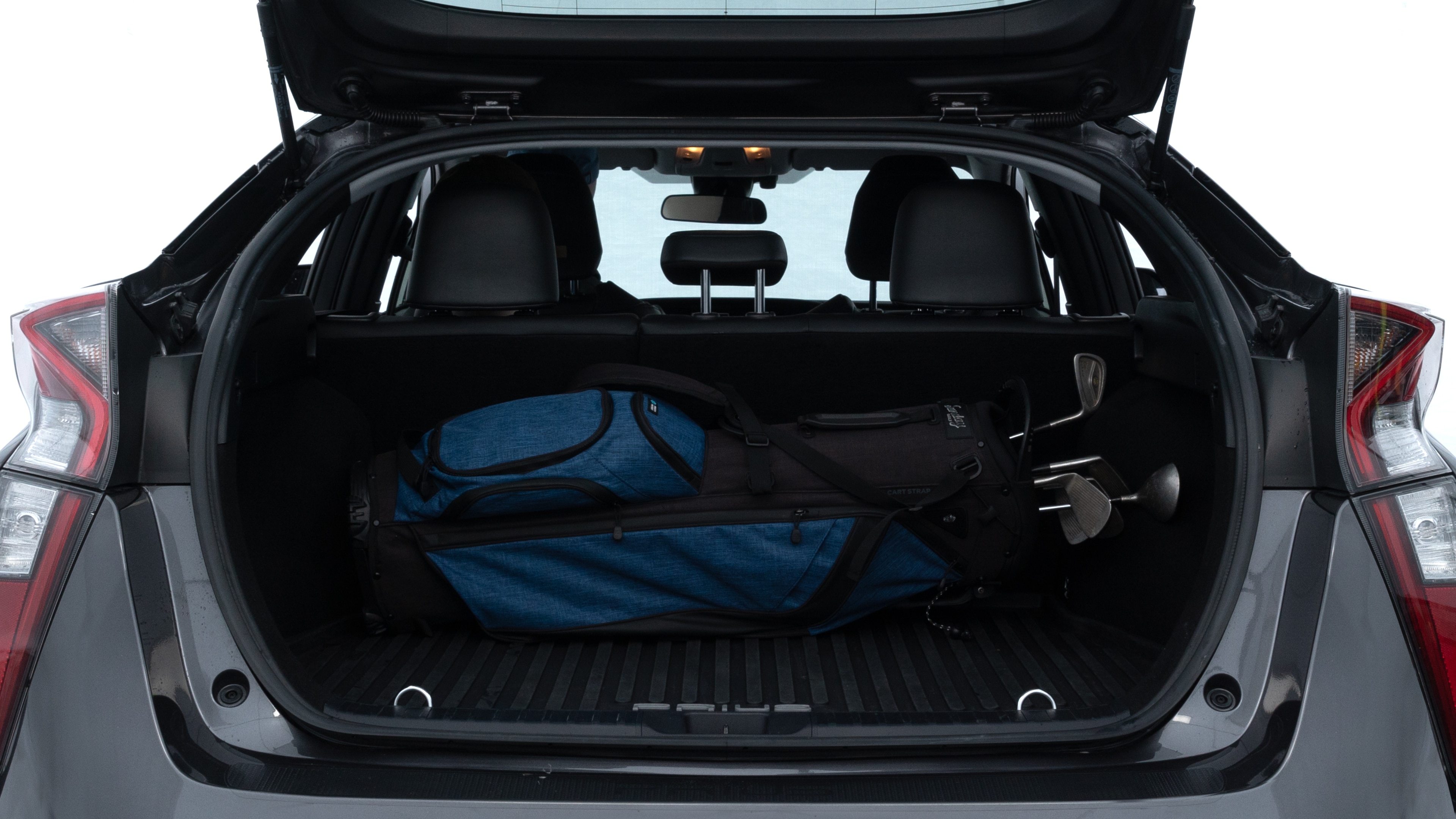 The trunk lid is open showing full view of the trunk. A baby stroller, three grocery carriers, two camping chairs in the carrying bag, and a set of golf clubs are placed inside.