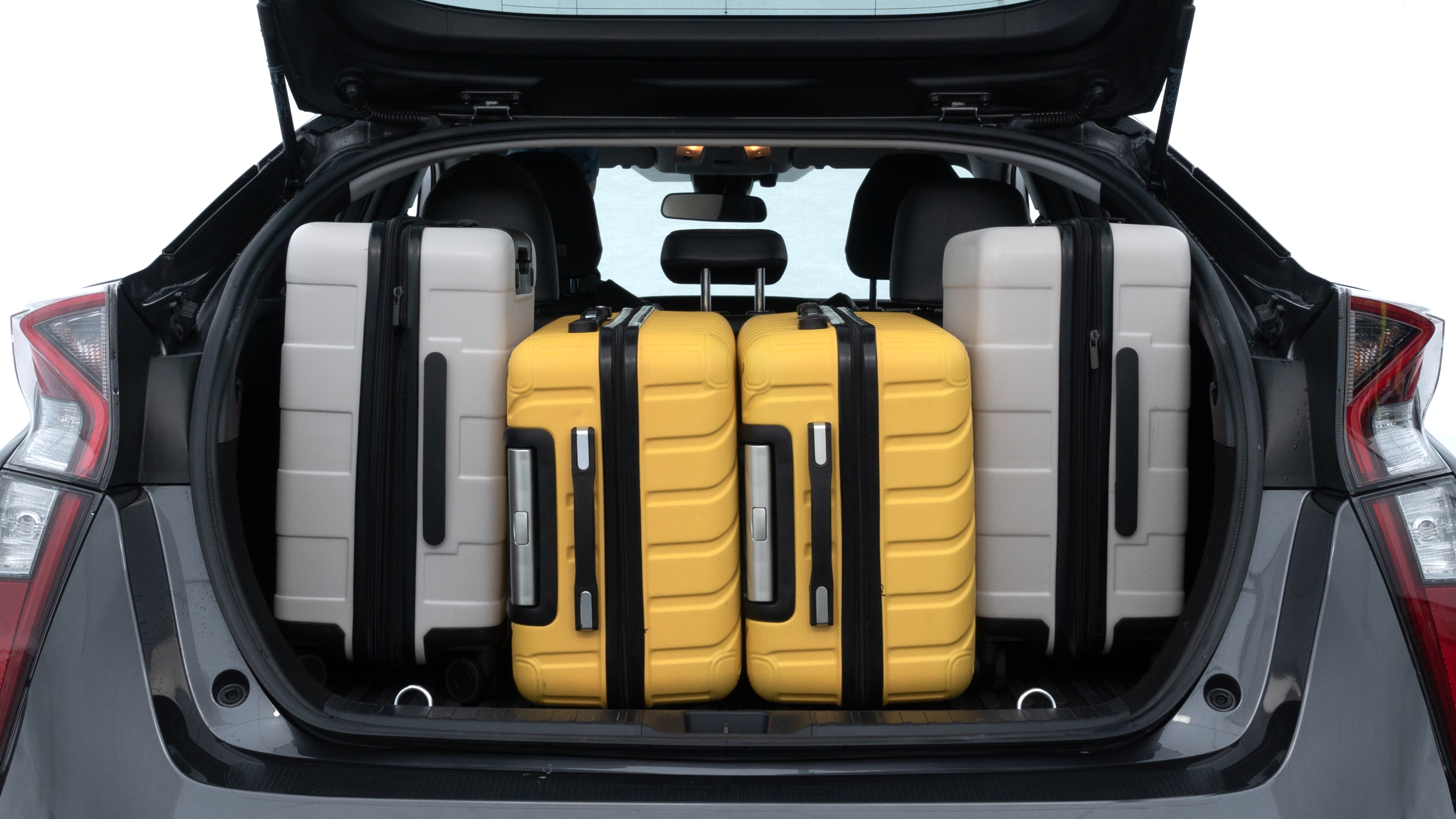 The trunk lid is open, showing full view of the trunk space. Two medium and two small suitcases are placed inside.