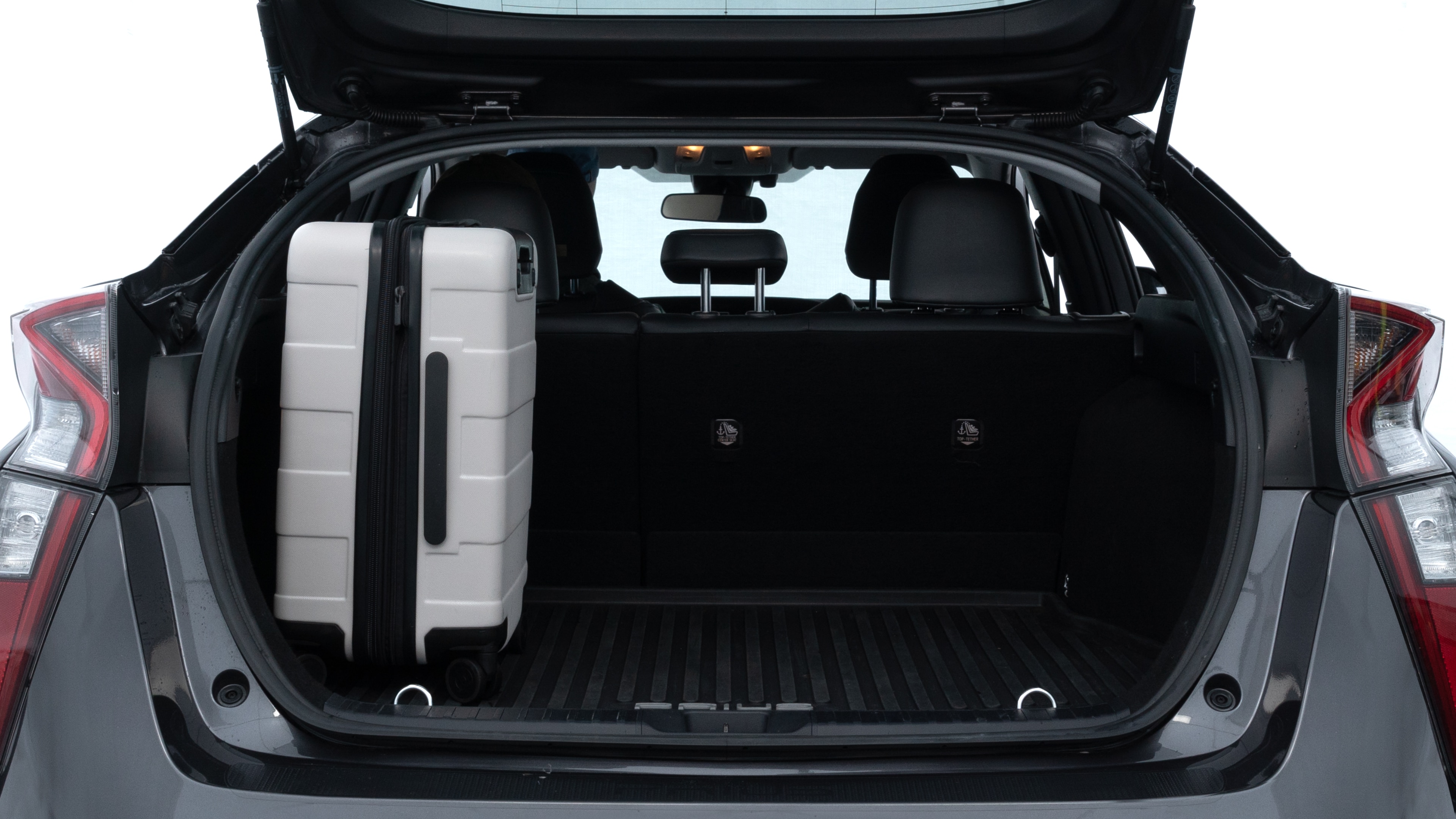 The trunk lid is open, showing full view of the trunk space. Two medium and two small suitcases are placed inside.
