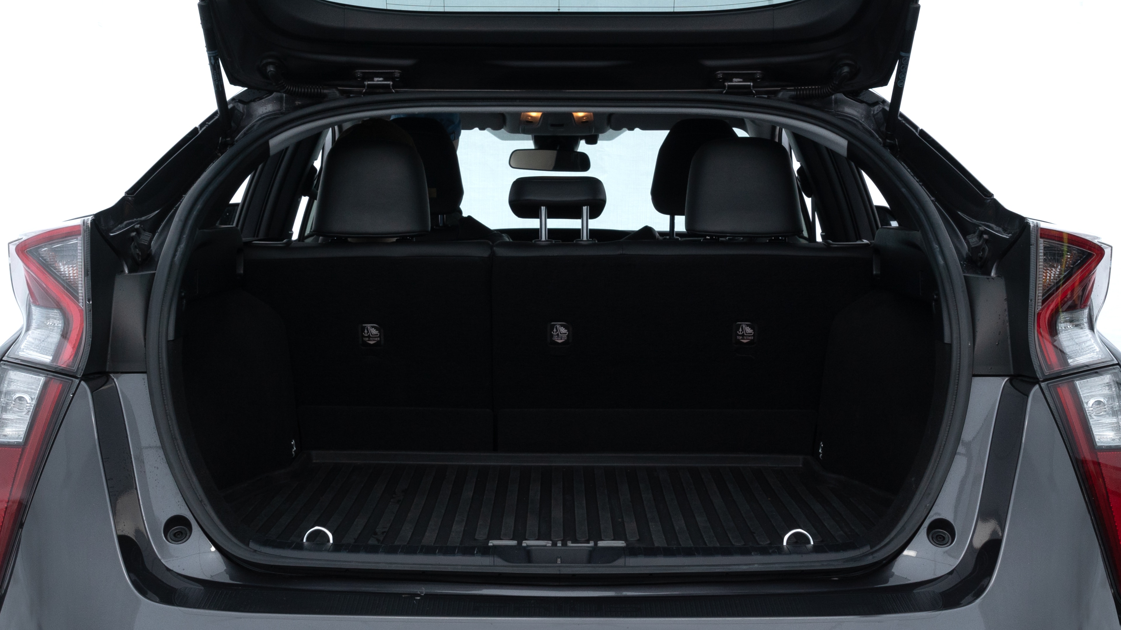 The trunk lid is open, showing full view of the trunk space. Two medium and two small suitcases are placed inside.