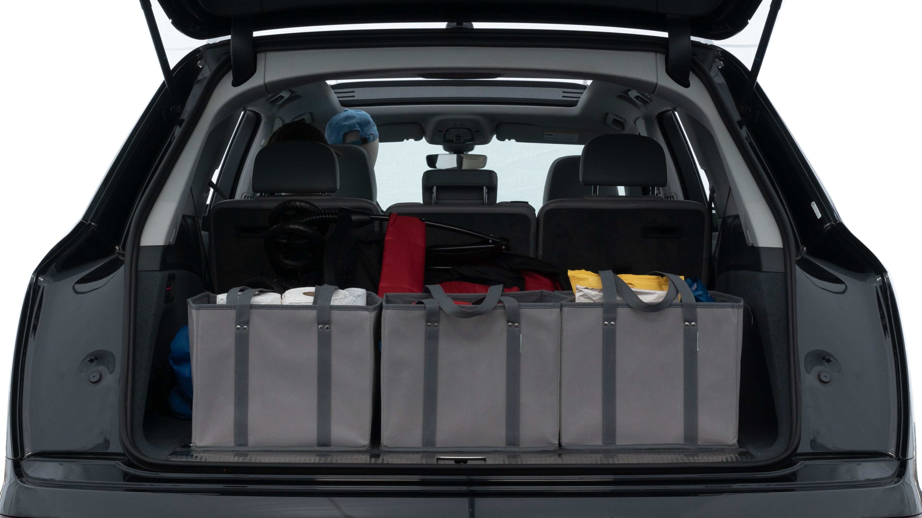 The trunk lid is open showing full view of the trunk. A baby stroller, three grocery carriers, two camping chairs in the carrying bag, and a set of golf clubs are placed inside.