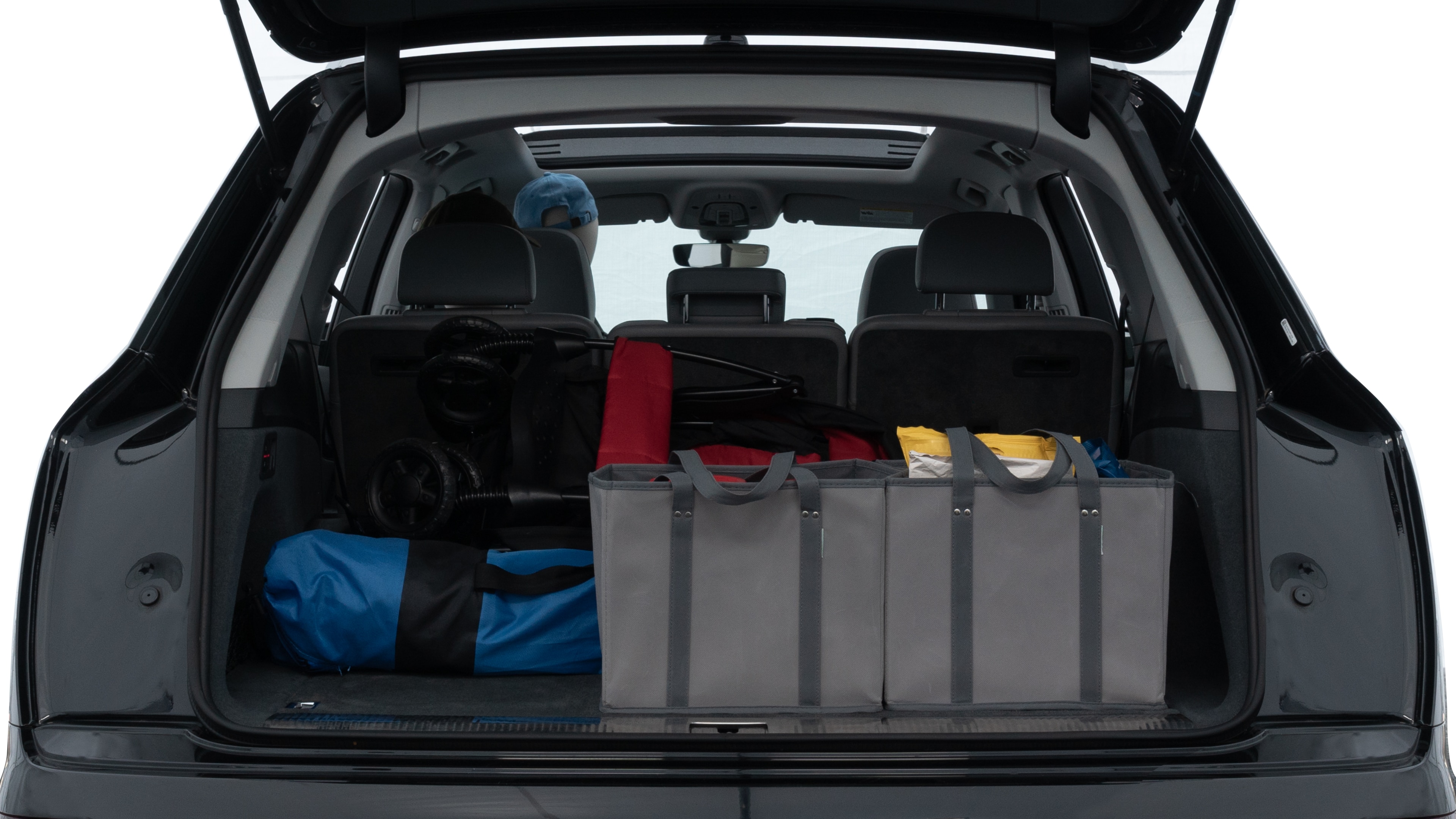The trunk lid is open showing full view of the trunk. A baby stroller, three grocery carriers, two camping chairs in the carrying bag, and a set of golf clubs are placed inside.