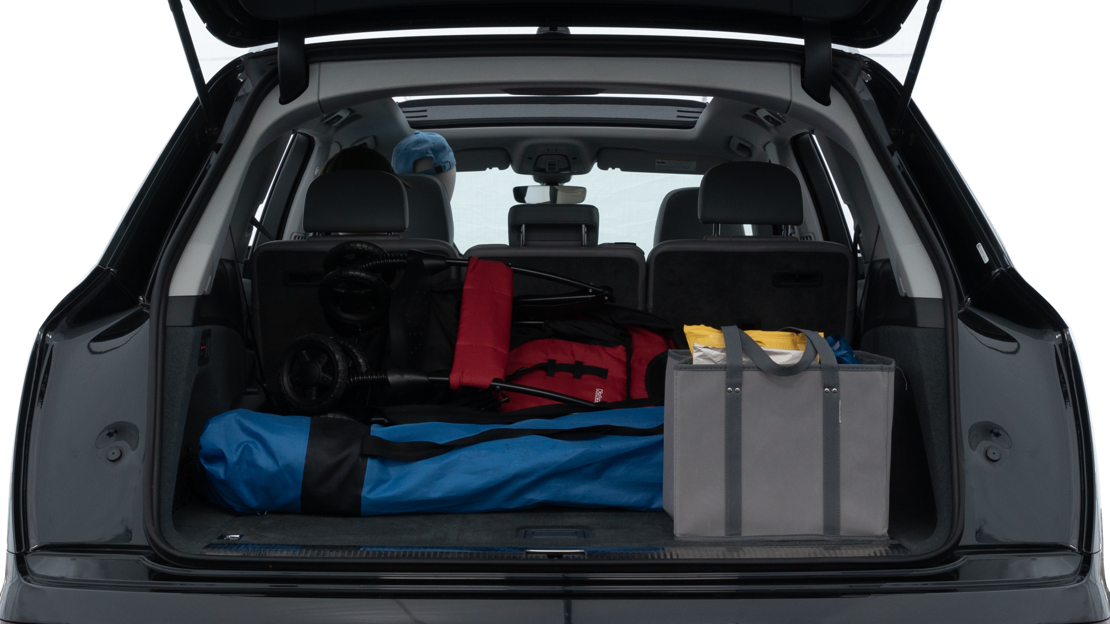 The trunk lid is open showing full view of the trunk. A baby stroller, three grocery carriers, two camping chairs in the carrying bag, and a set of golf clubs are placed inside.