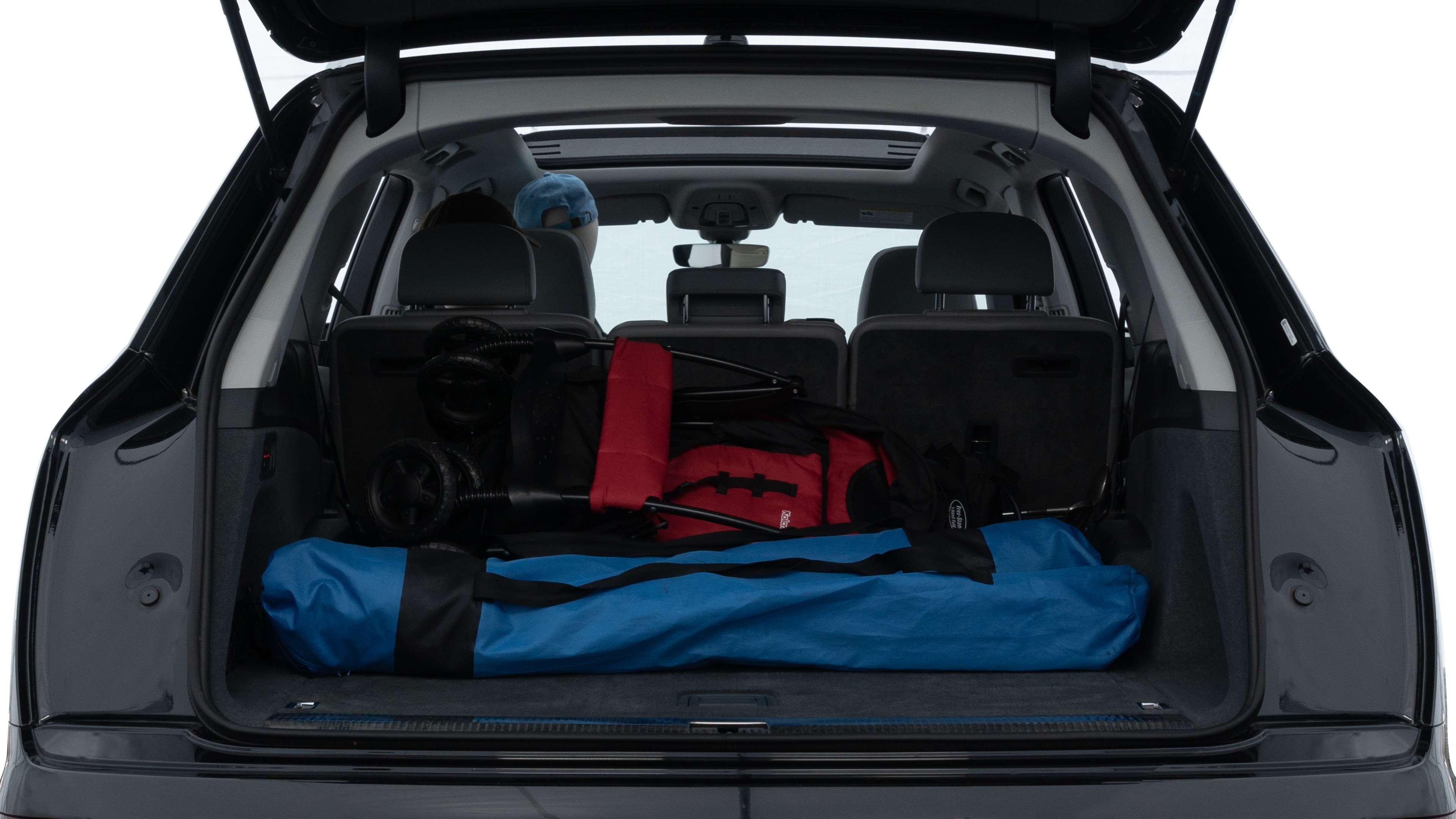 The trunk lid is open showing full view of the trunk. A baby stroller, three grocery carriers, two camping chairs in the carrying bag, and a set of golf clubs are placed inside.